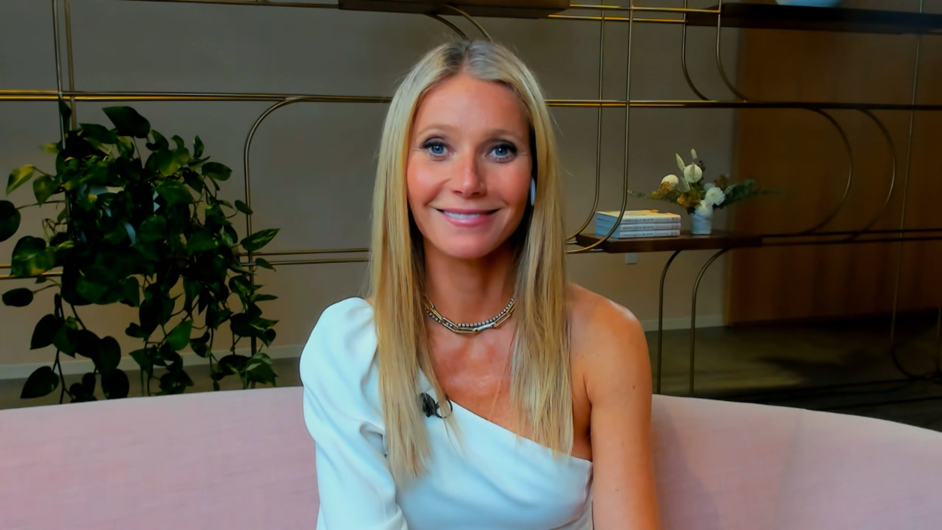 Gwyneth Paltrow apparaît dans l'émission « Watch What Happens Live With Andy Cohen » en 2021. Elle porte un haut blanc chic à une épaule, associé à un collier à chaîne doré. Ses cheveux blonds raides sont séparés au milieu et lissés, tandis que son maquillage doux et ses lèvres roses lui confèrent un look moderne et naturellement soigné pour son passage à la télévision.