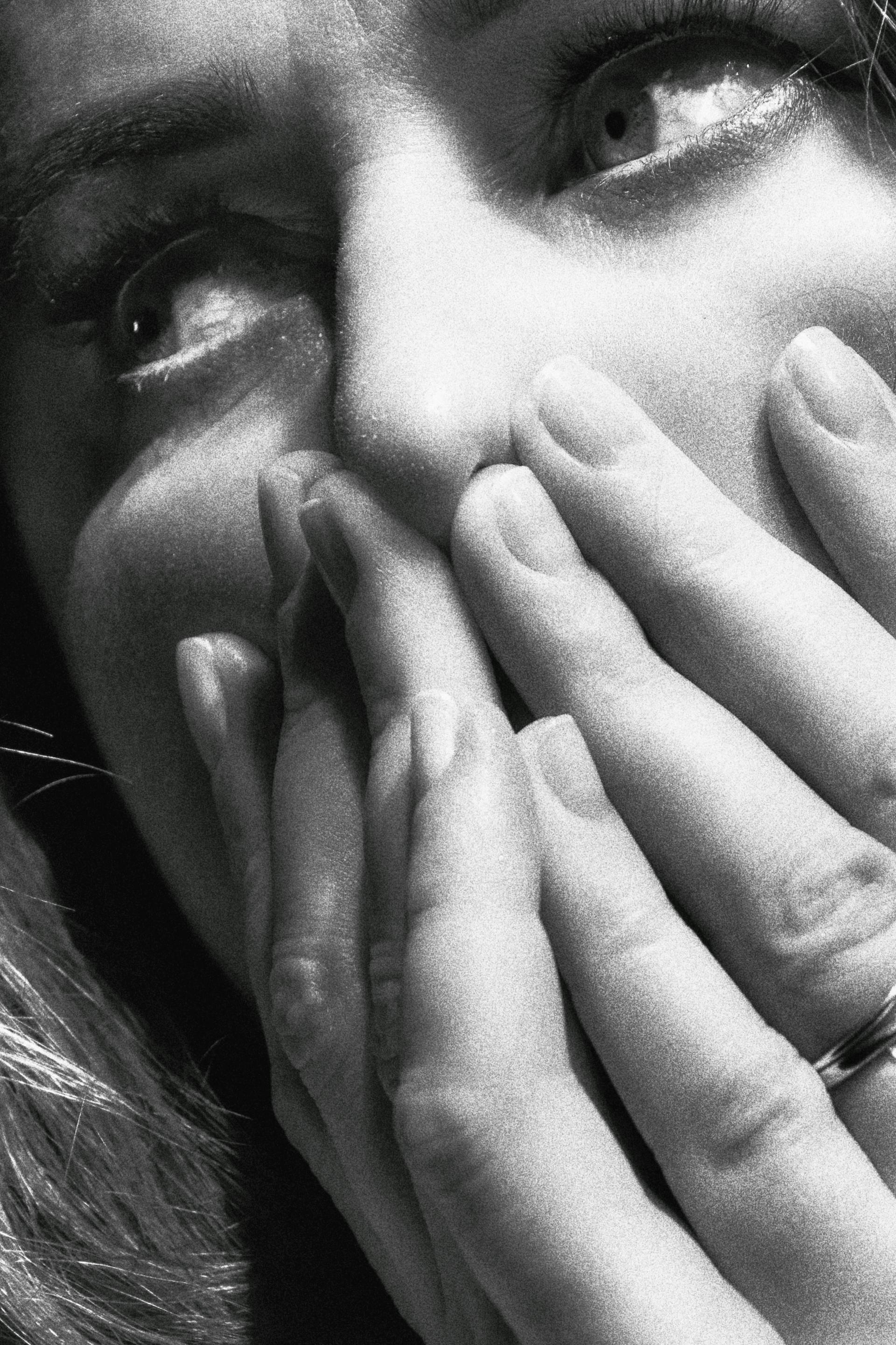Photo en niveaux de gris d'une femme se couvrant le visage avec ses mains | Source : Pexels