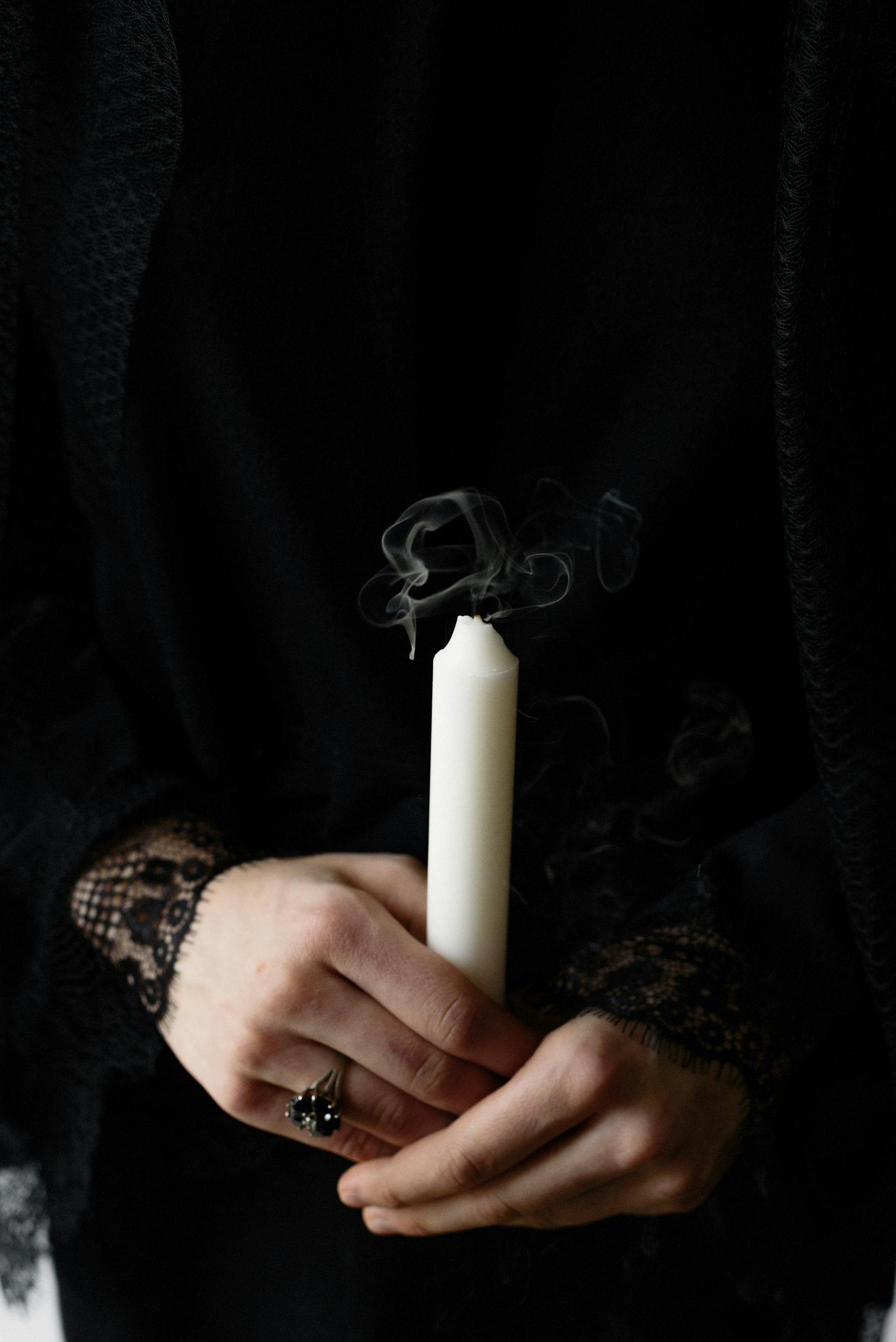 Gros plan d'une femme tenant une bougie blanche | Source : Pexels