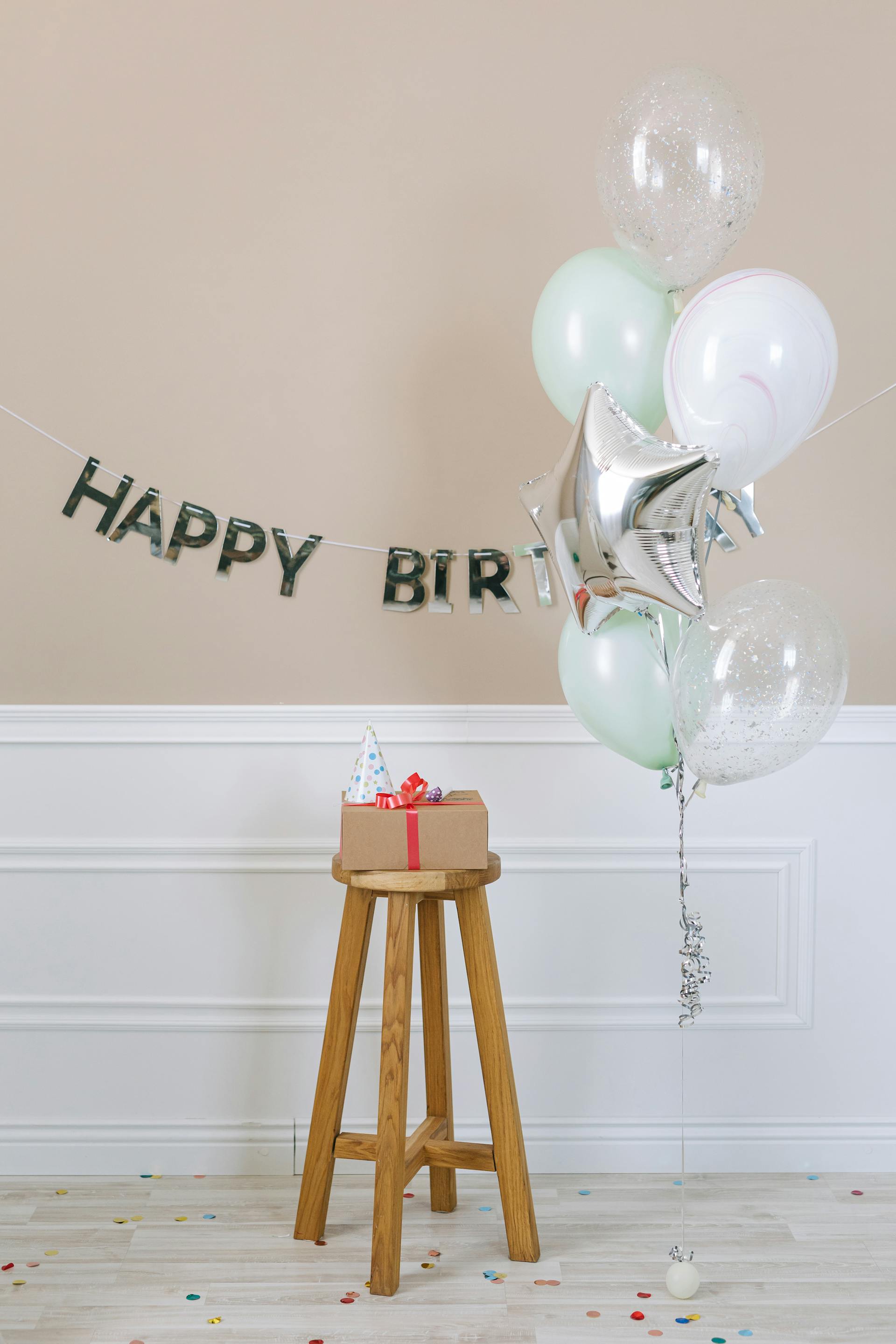 Un cadeau d'anniversaire posé sur un tabouret en bois placé à côté de ballons | Source : Pexels