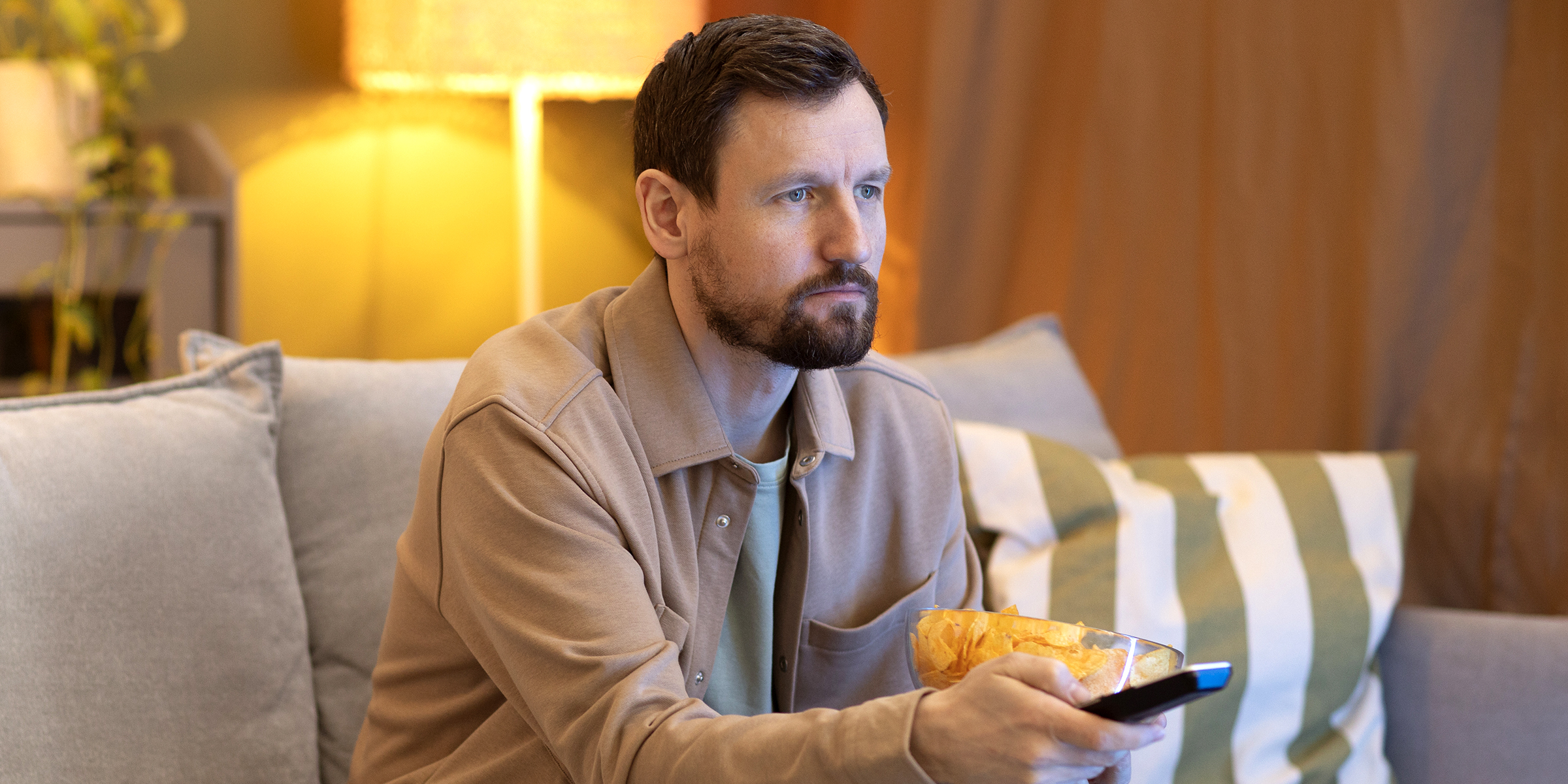 Un homme qui regarde la télévision sur un canapé | Source : Freepik