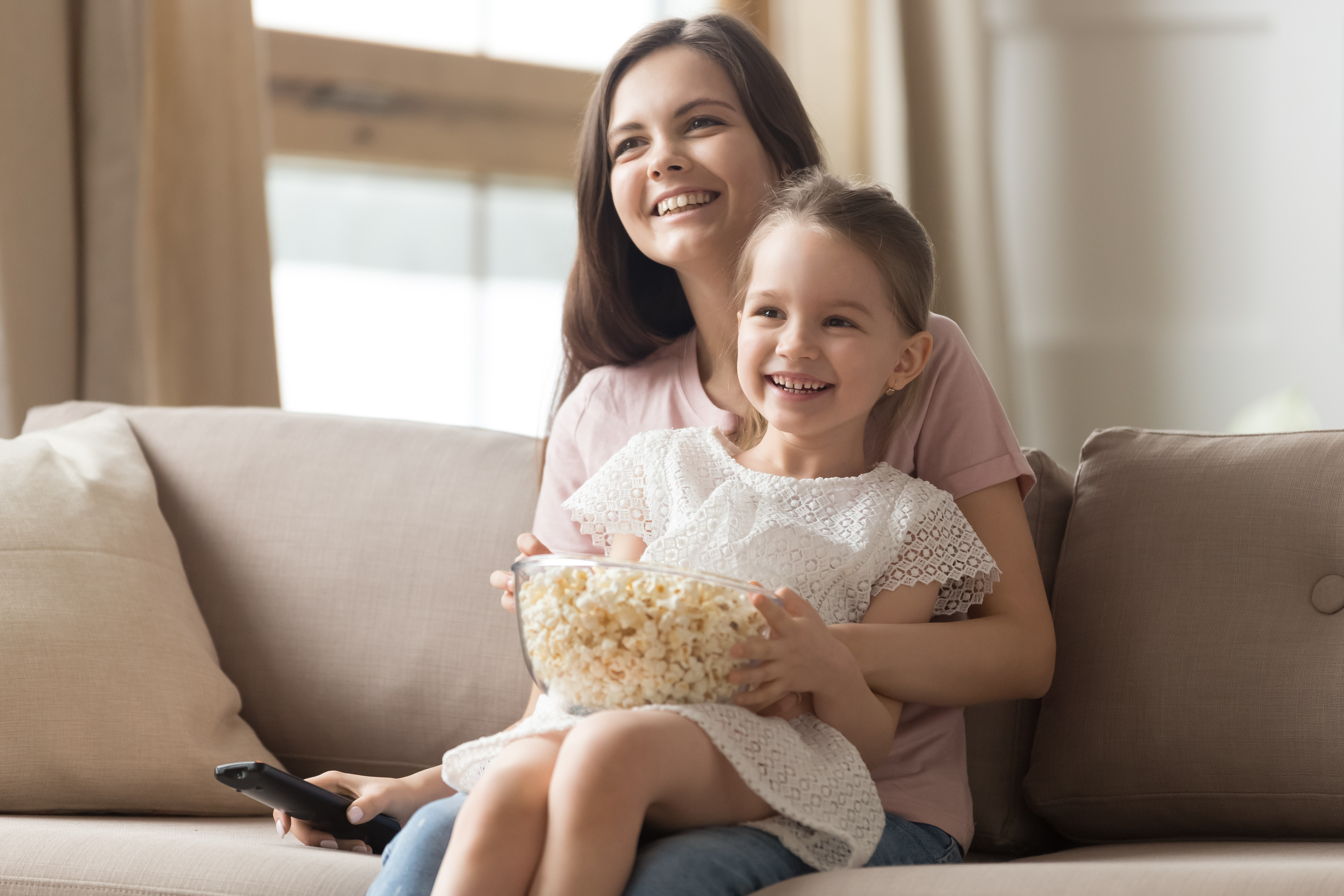 Une jeune femme heureuse avec une petite fille qui sourit sur ses genoux | Source : Shutterstock