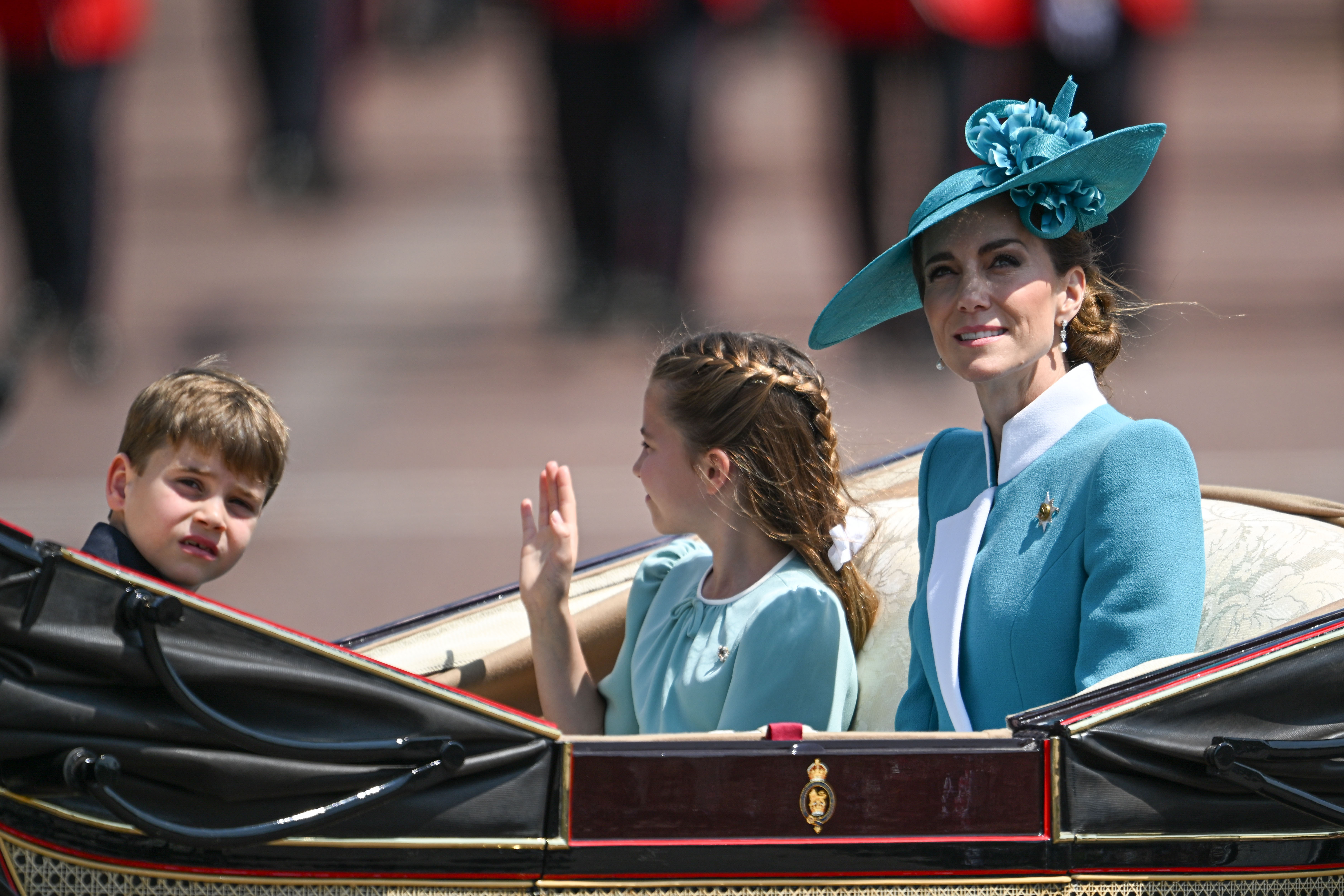 La princesse Charlotte salue la foule en montant dans la calèche avec la princesse Catherine et le prince Louis.