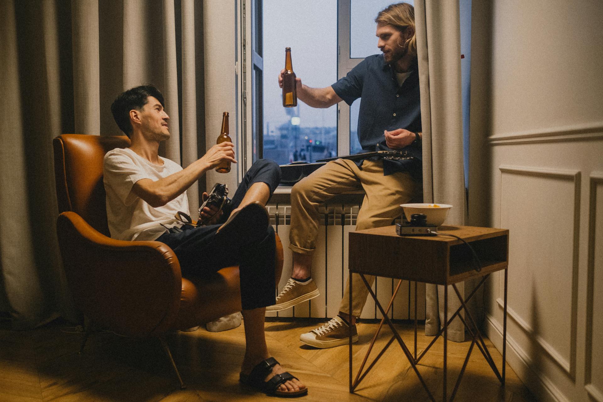Deux hommes trinquent avec leurs bouteilles de bière | Source : Pexels