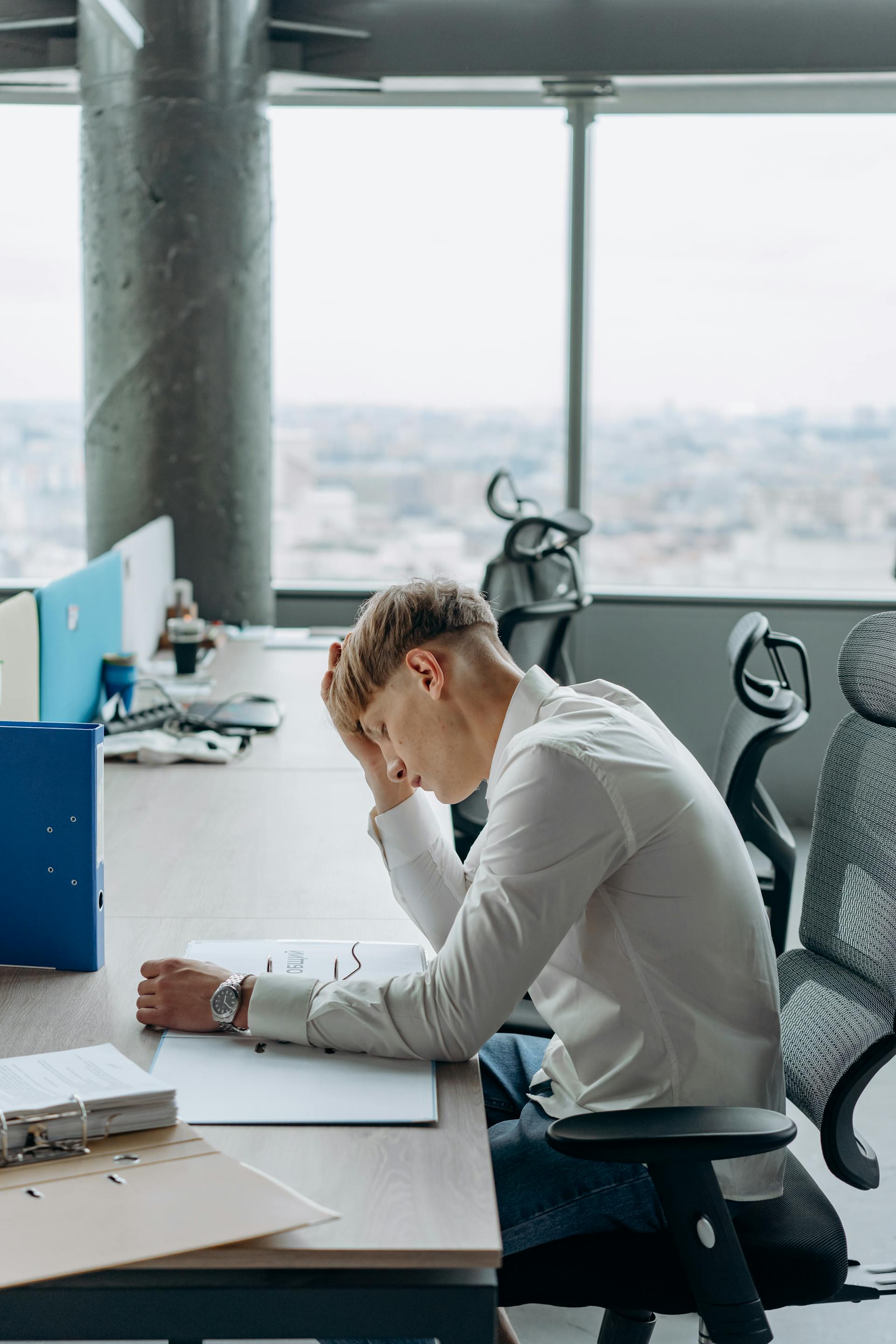 Un homme assis dans le bureau avec une main sur la tête | Source : Pexels