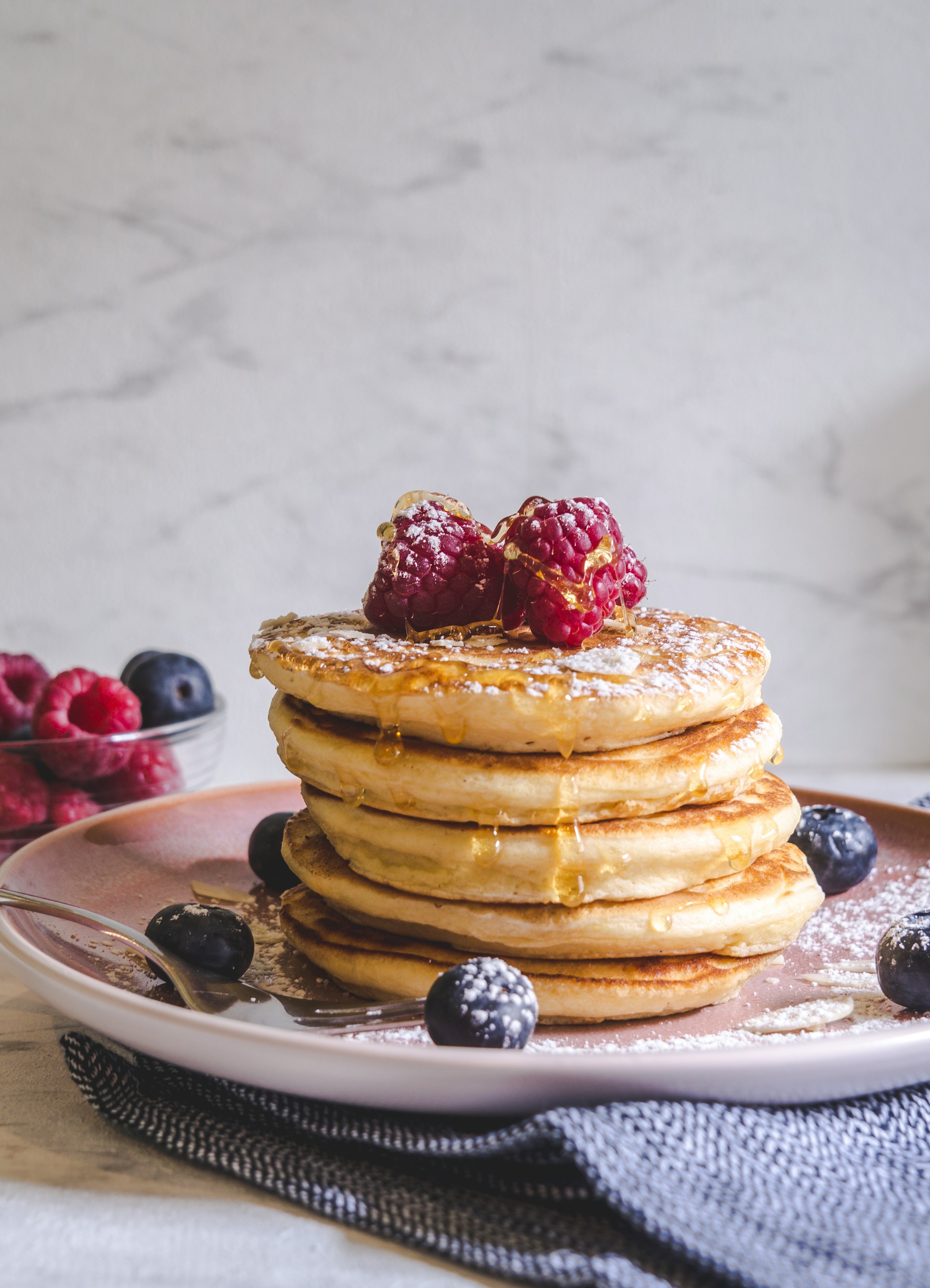 Une photo montrant des crêpes avec des baies posées sur une assiette en céramique blanche | Source : Unsplash