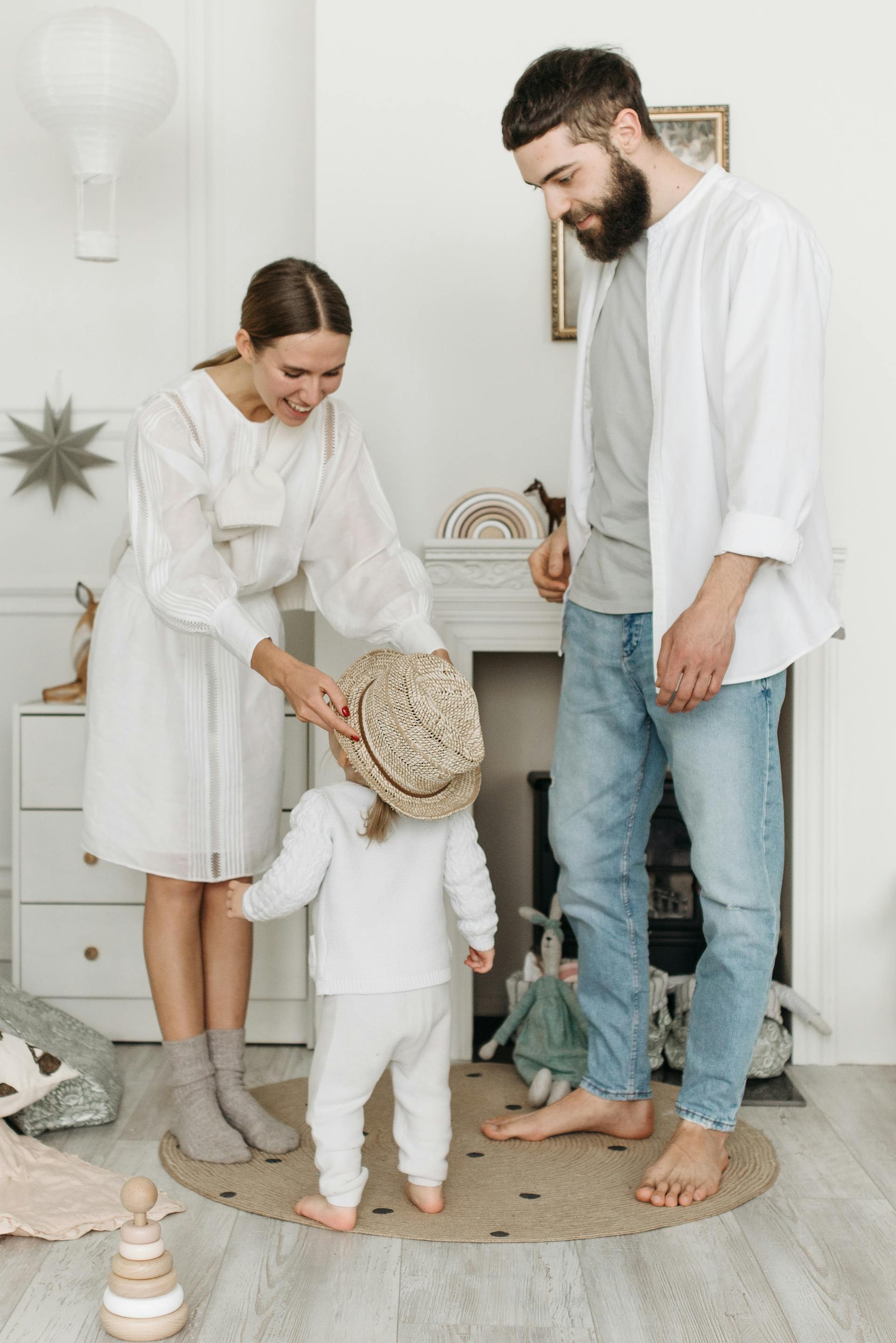 Un homme qui regarde une femme mettre un chapeau à une petite fille | Source : Pexels