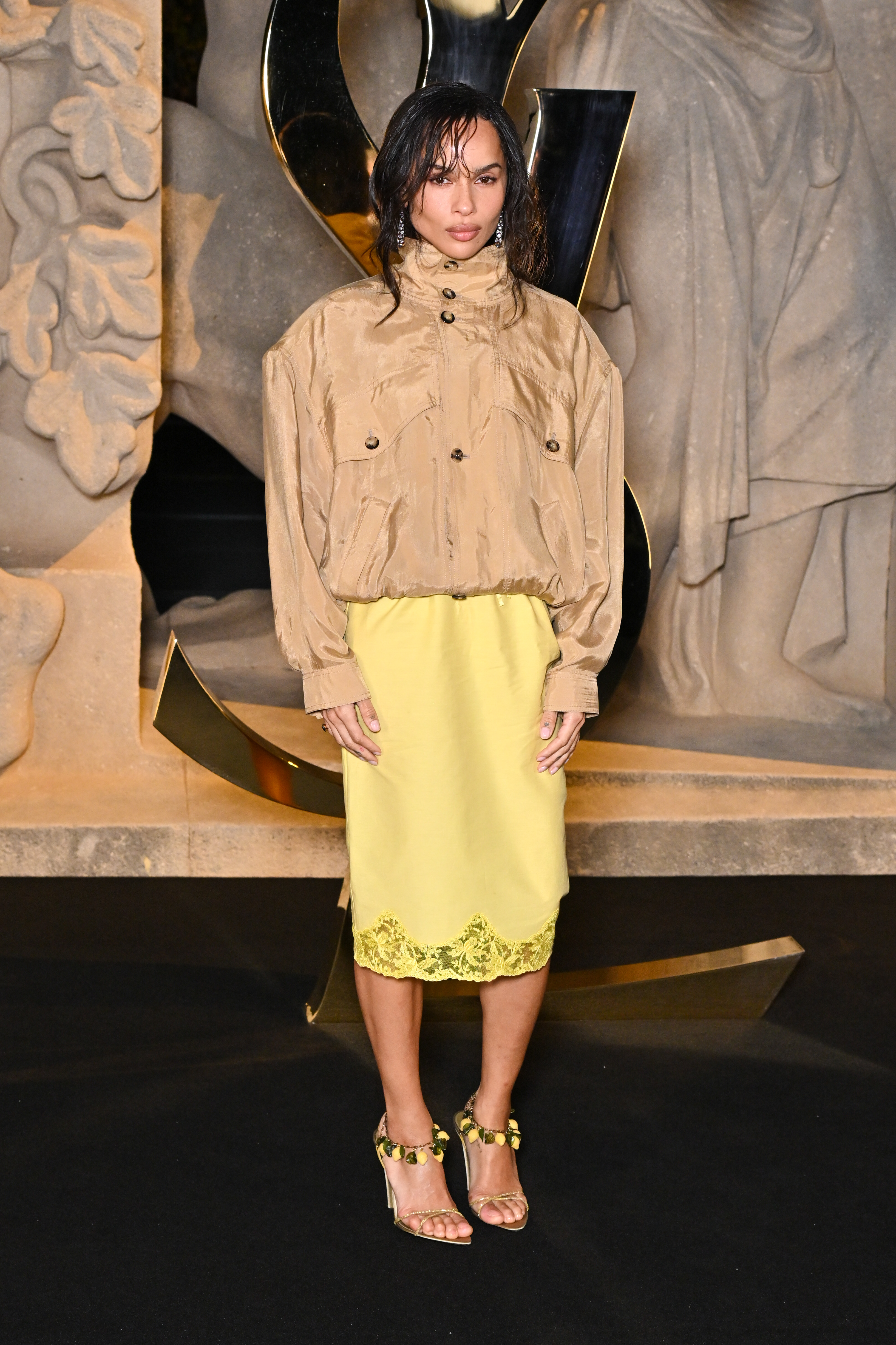 Zoë Kravitz assiste au défilé Saint Laurent Femme Printemps/Été 2026 lors de la Fashion Week de Paris, en France, et fait tourner les têtes dans une jupe nuisette en soie. Elle l'a associée à un coupe-vent beige, des sandales à lanières ornées de bijoux et une pochette orange qui attire tous les regards.