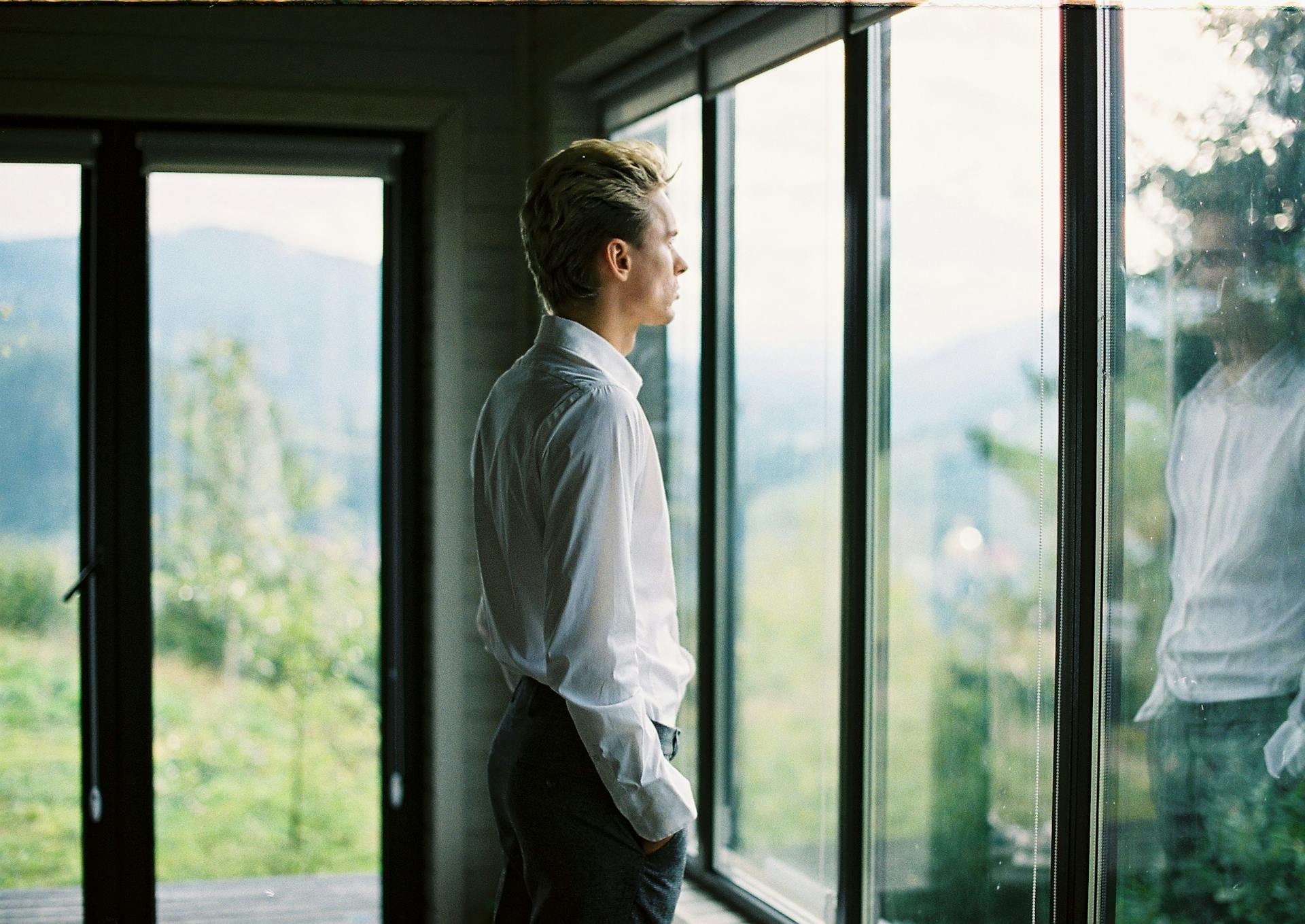 Un homme debout près d'une fenêtre en verre | Source : Pexels