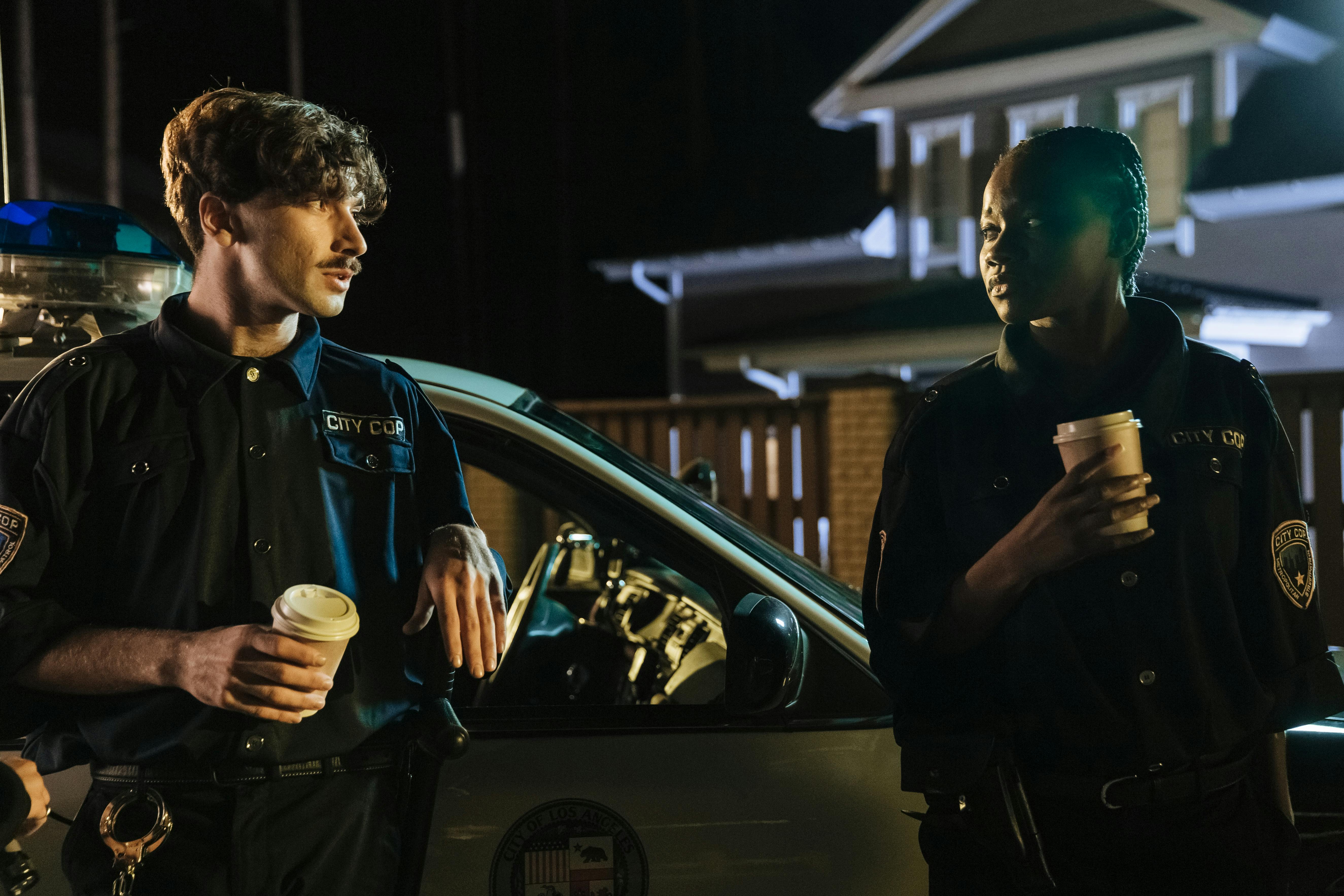 Des policiers se tiennent à côté d'une voiture de patrouille | Source : Pexels