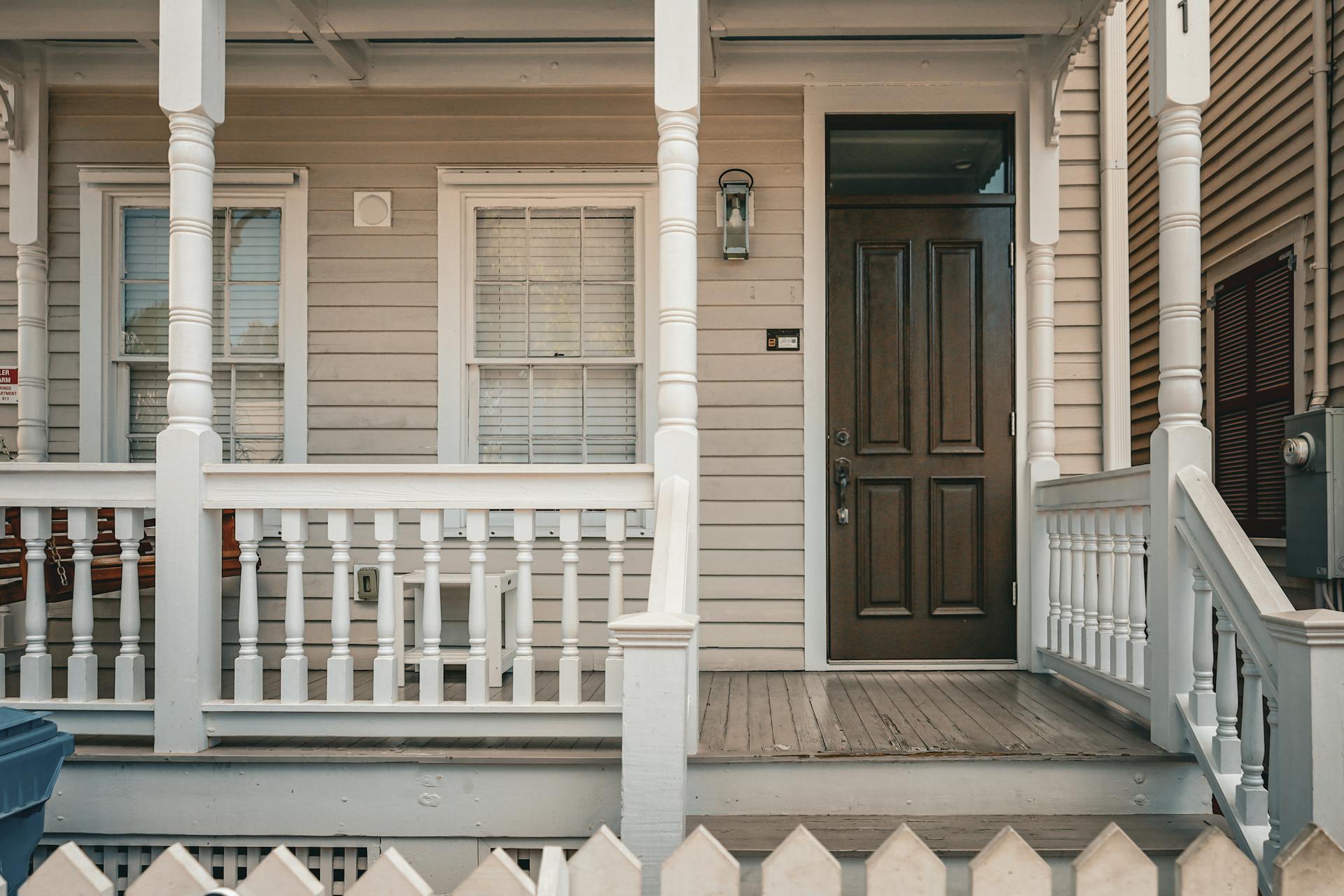 Un porche d'entrée confortable avec une porte marron foncé et une clôture blanche | Source : Pexels
