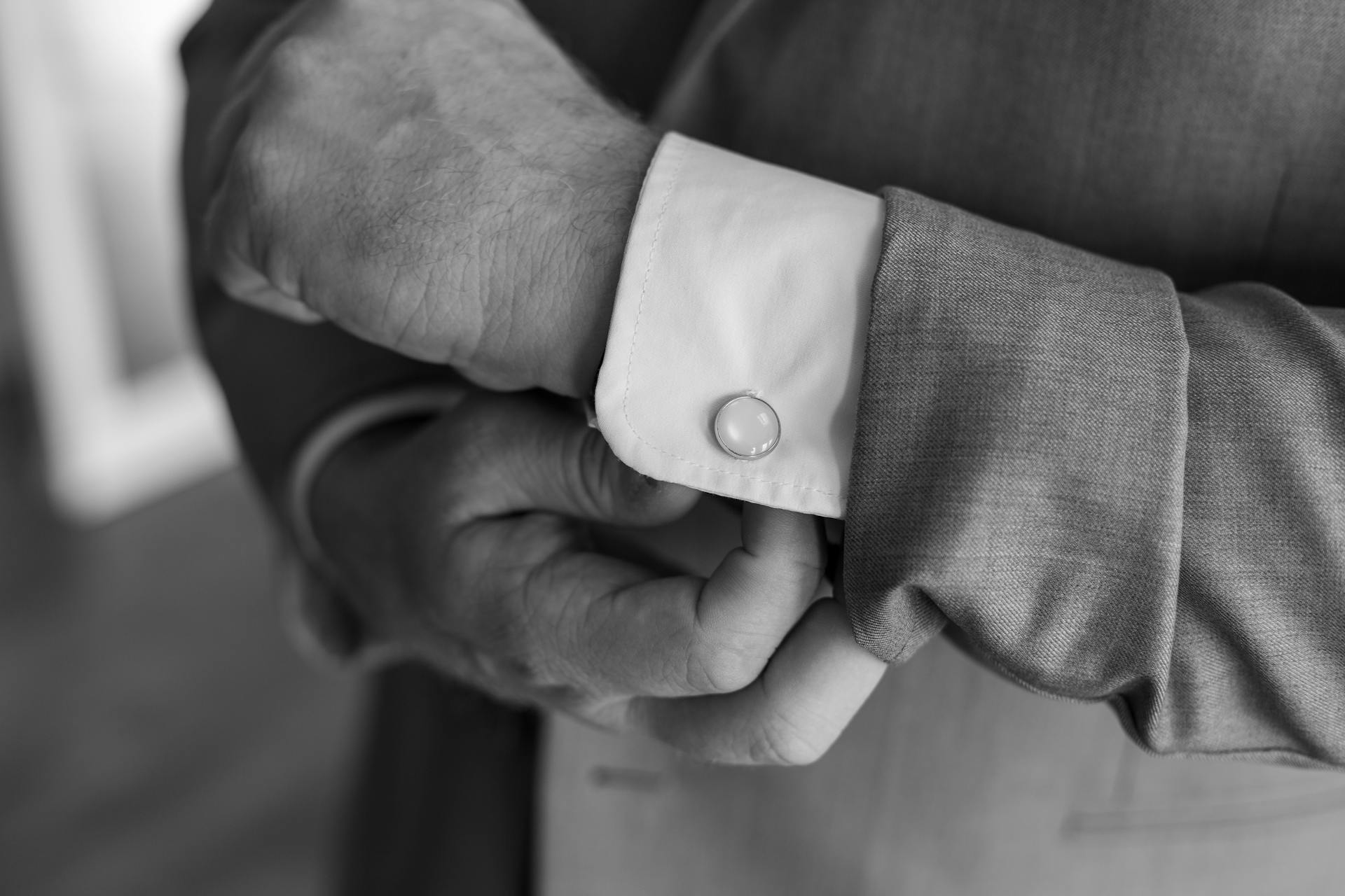 Photo en niveaux de gris d'un homme ajustant son bouton de manchette | Source : Pexels