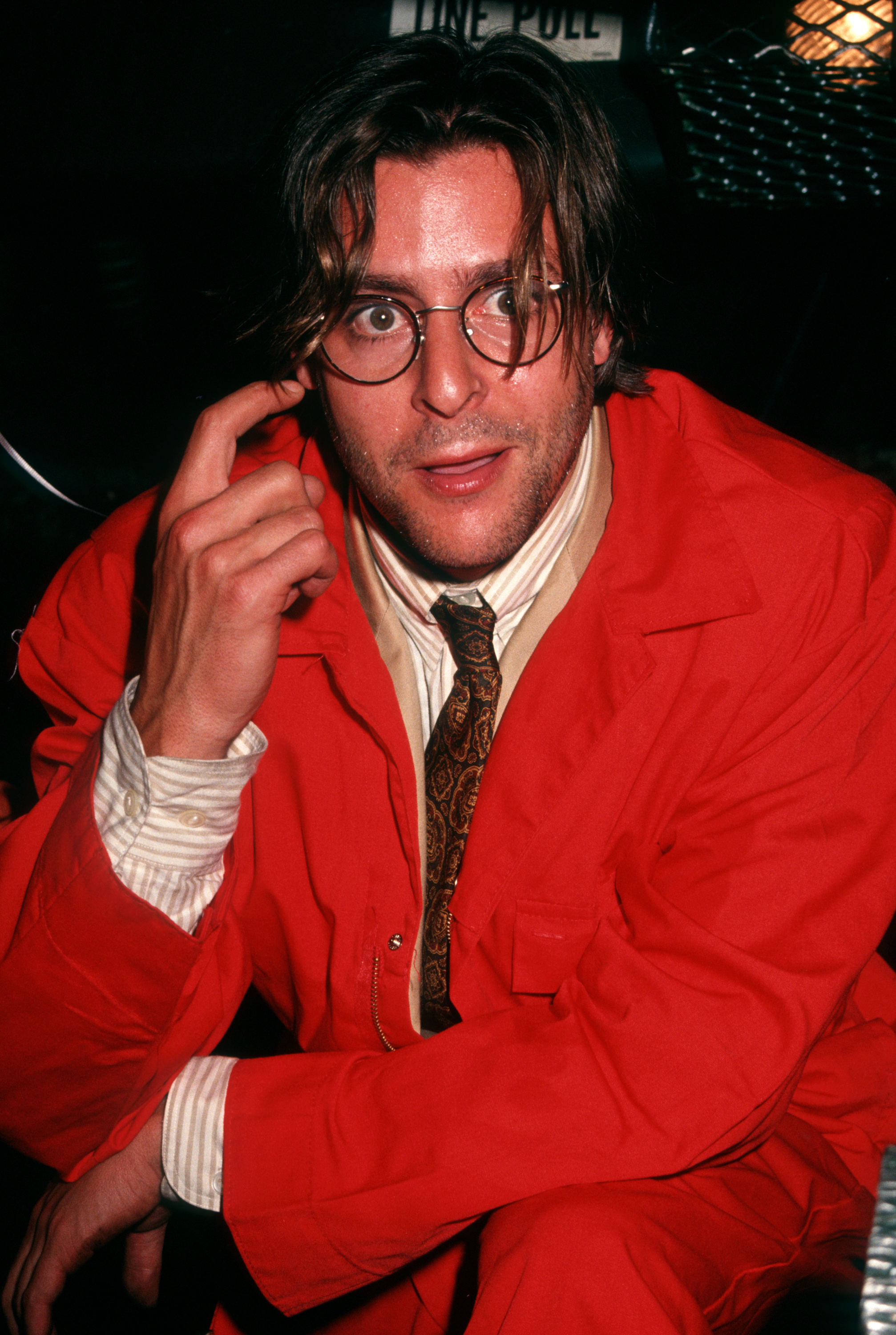 Dans une combinaison rouge vif, avec des lunettes à monture ronde et une cravate à motifs, l'acteur a pris une pose décontractée lors de la soirée de première de « The Dark Backward » à The Gas Station à New York. | Source: Getty Images