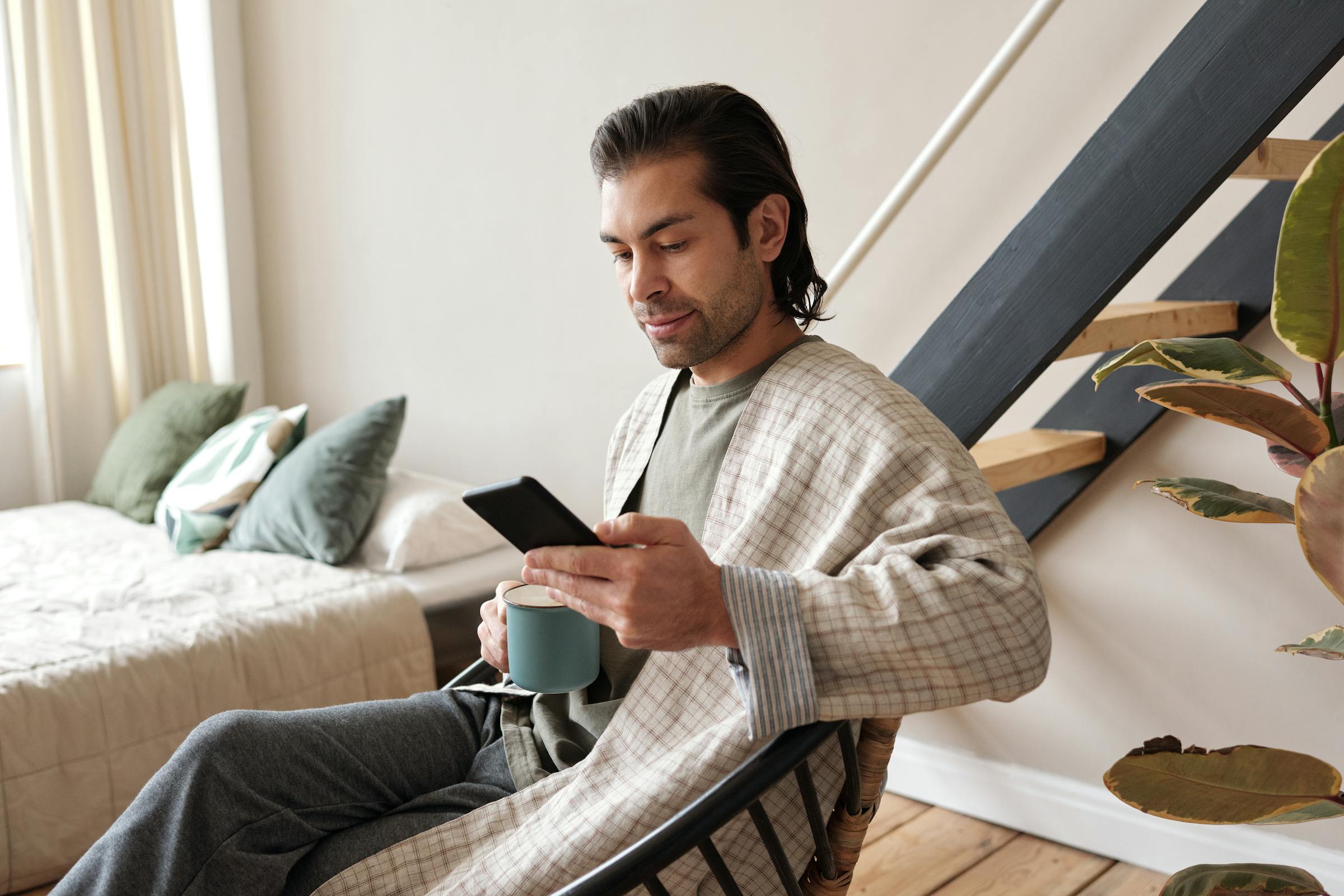 Un homme regardant son téléphone tout en buvant du café | Source : Pexels
