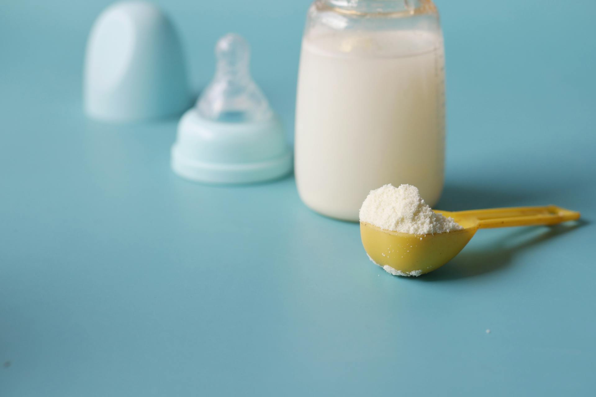 Gros plan sur une cuillère de lait en poudre posée à côté d'un biberon | Source : Pexels