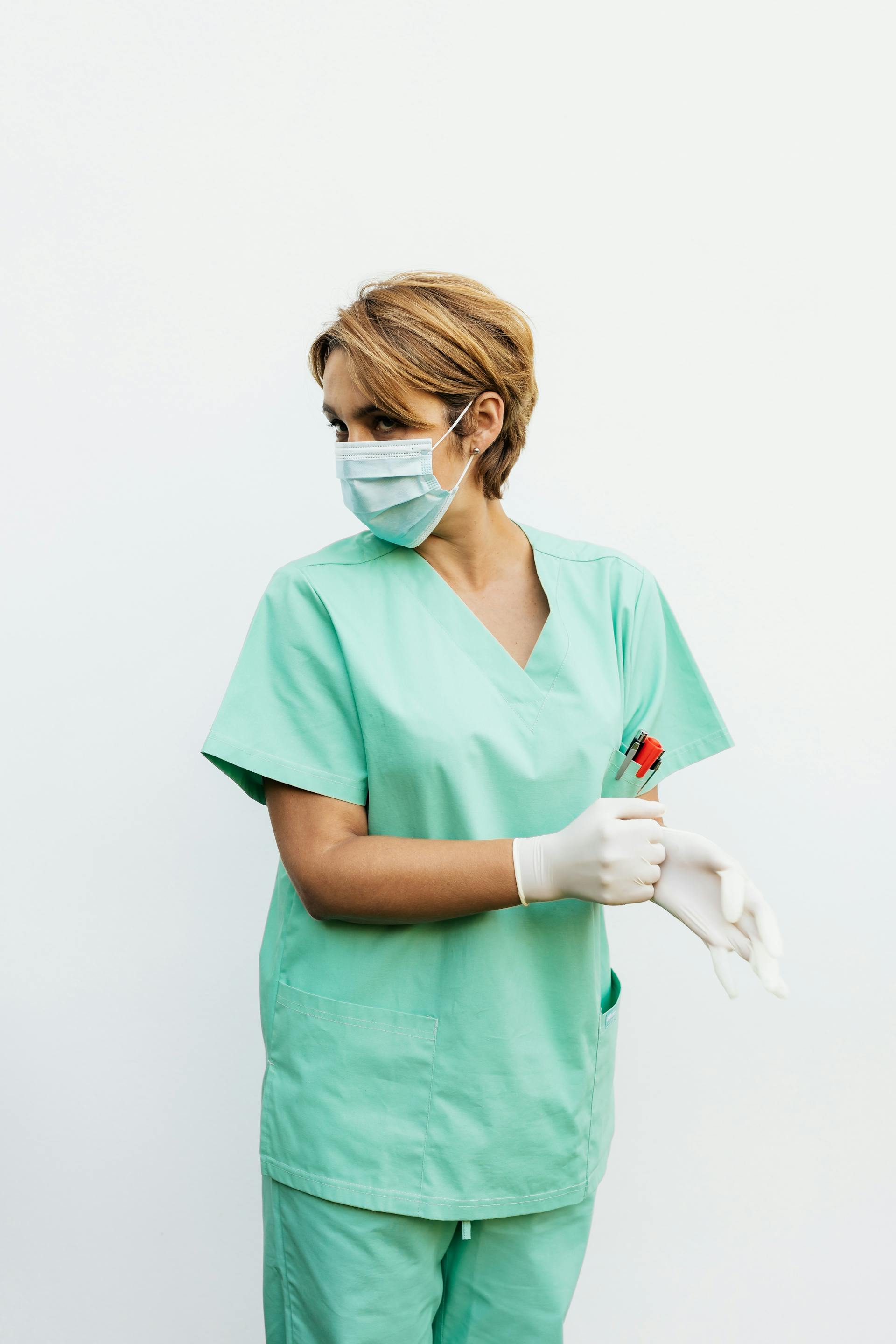 Une infirmière en blouse et masque de protection regarde en arrière | Source : Pexels