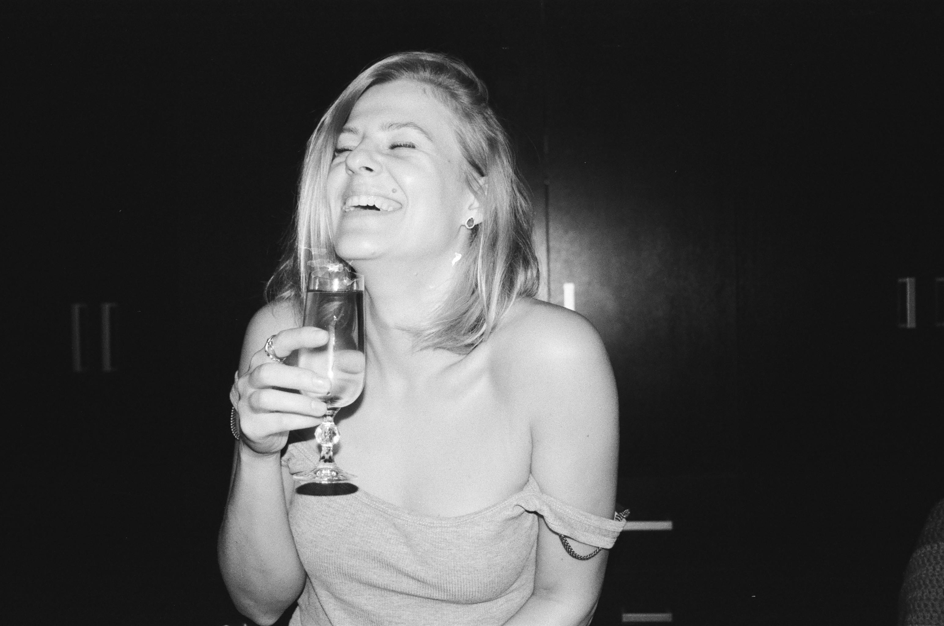 Une femme qui rit en tenant un verre | Source : Pexels