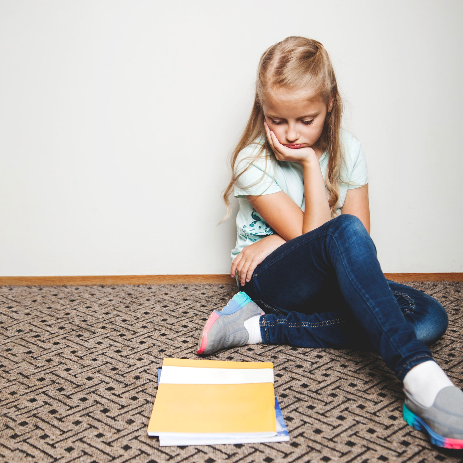 Une jeune fille triste qui regarde ses cahiers | Source : Freepik