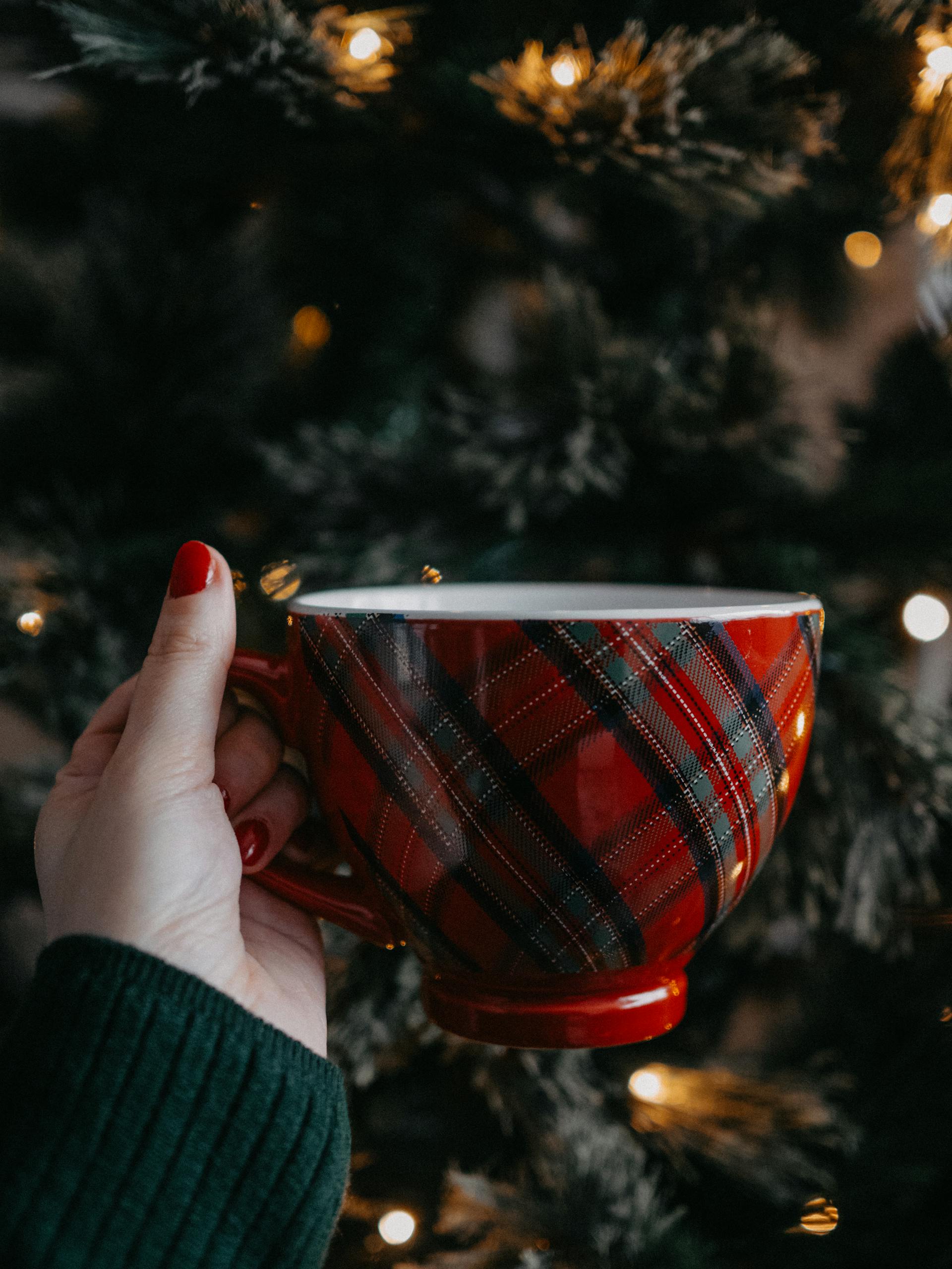Gros plan d'une femme tenant une tasse de thé pendant la fête de Noël | Source : Pexels