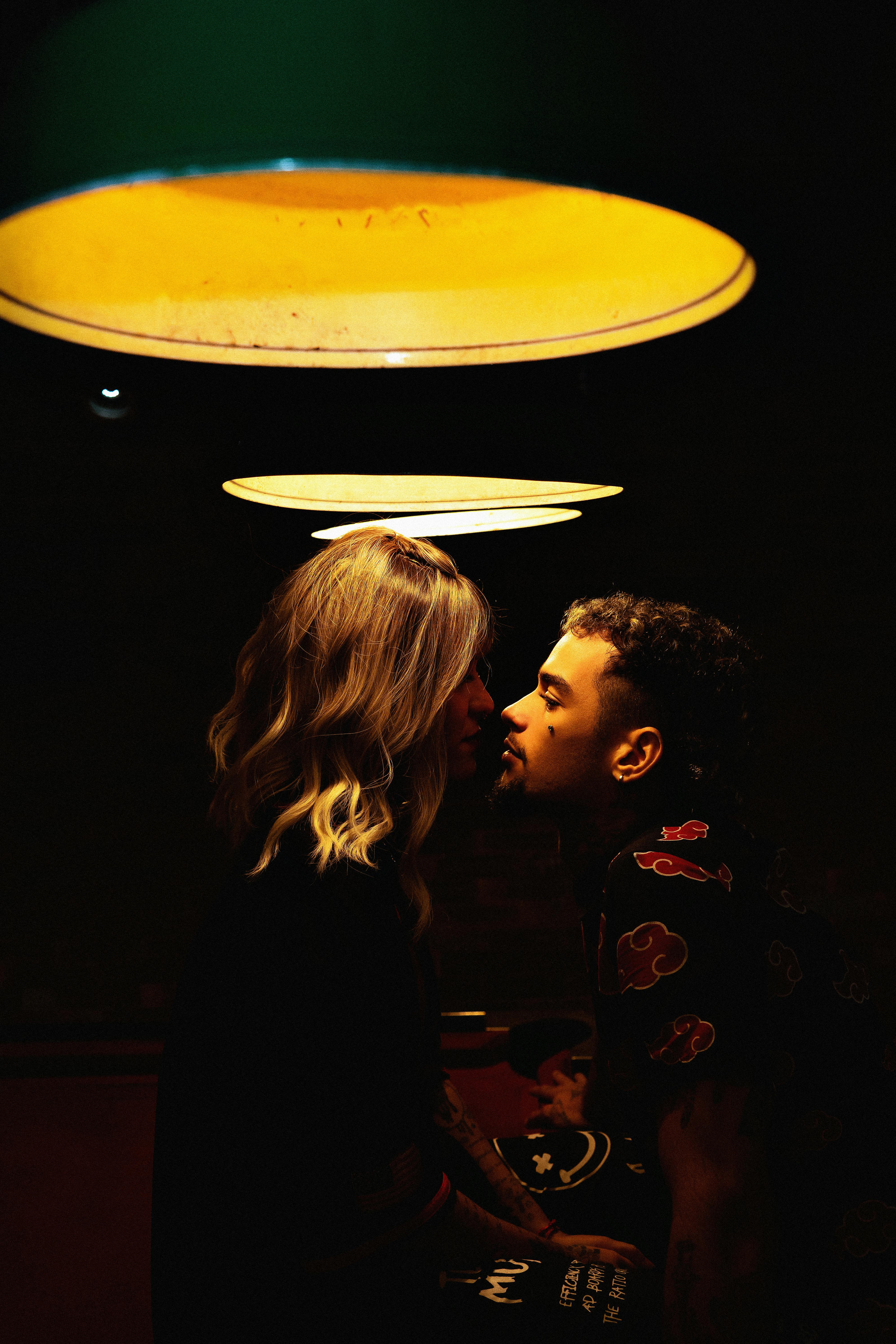 Un jeune homme et une jeune femme s'embrassant sous les lumières | Source : Pexels