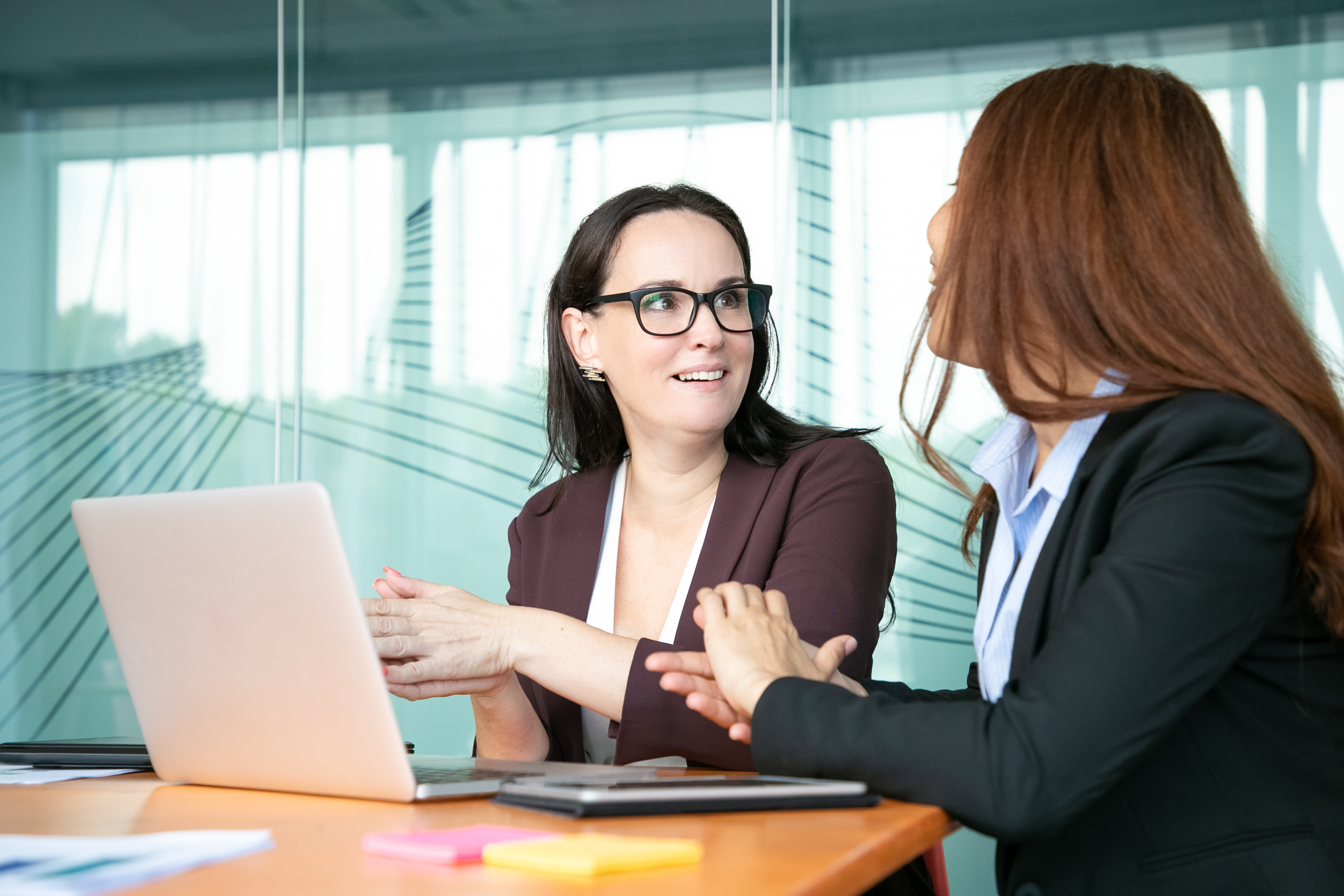 Une femme souriante discute avec sa collègue de travail | Source : Freepik