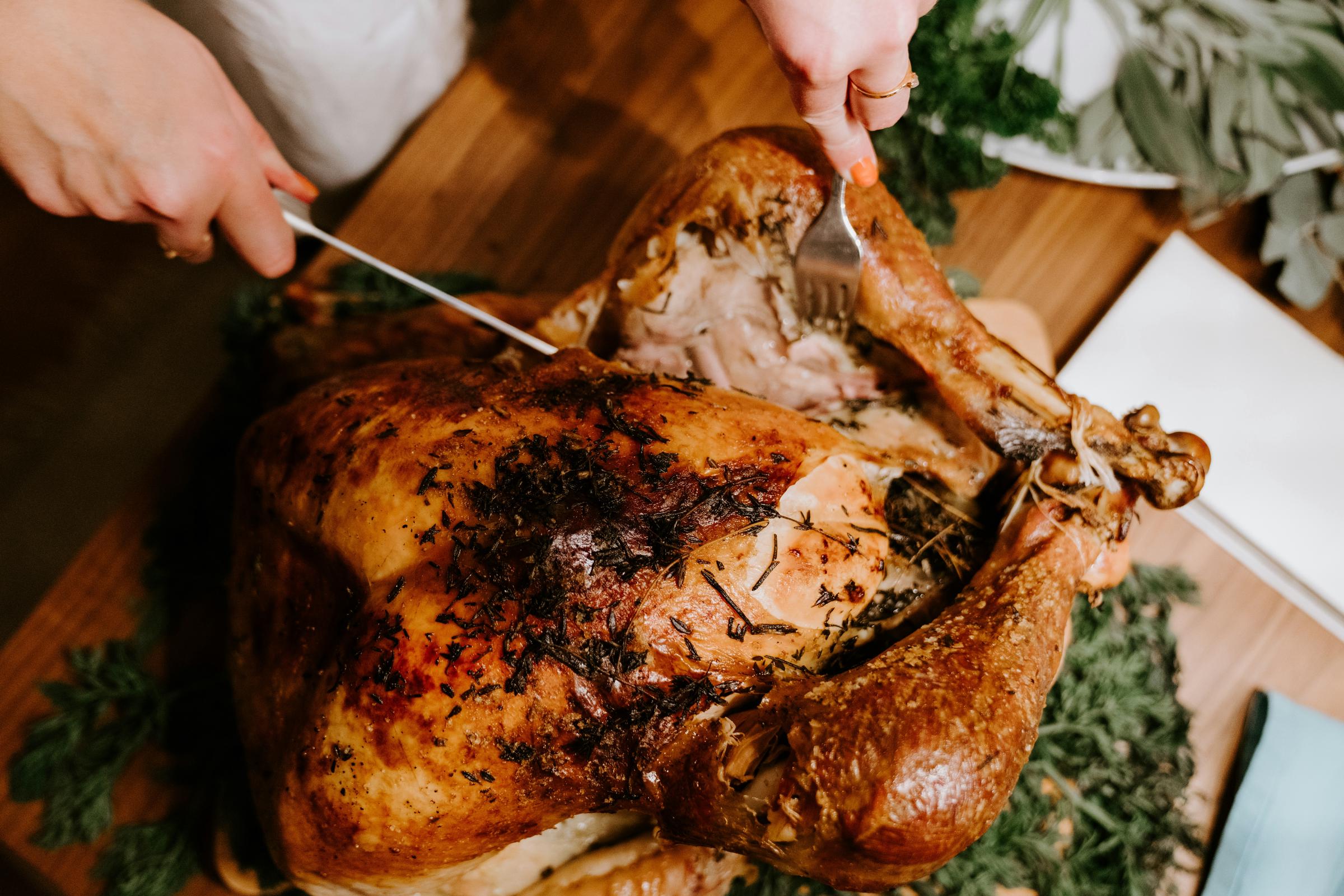 Une personne en train de découper un poulet rôti | Source : Unsplash