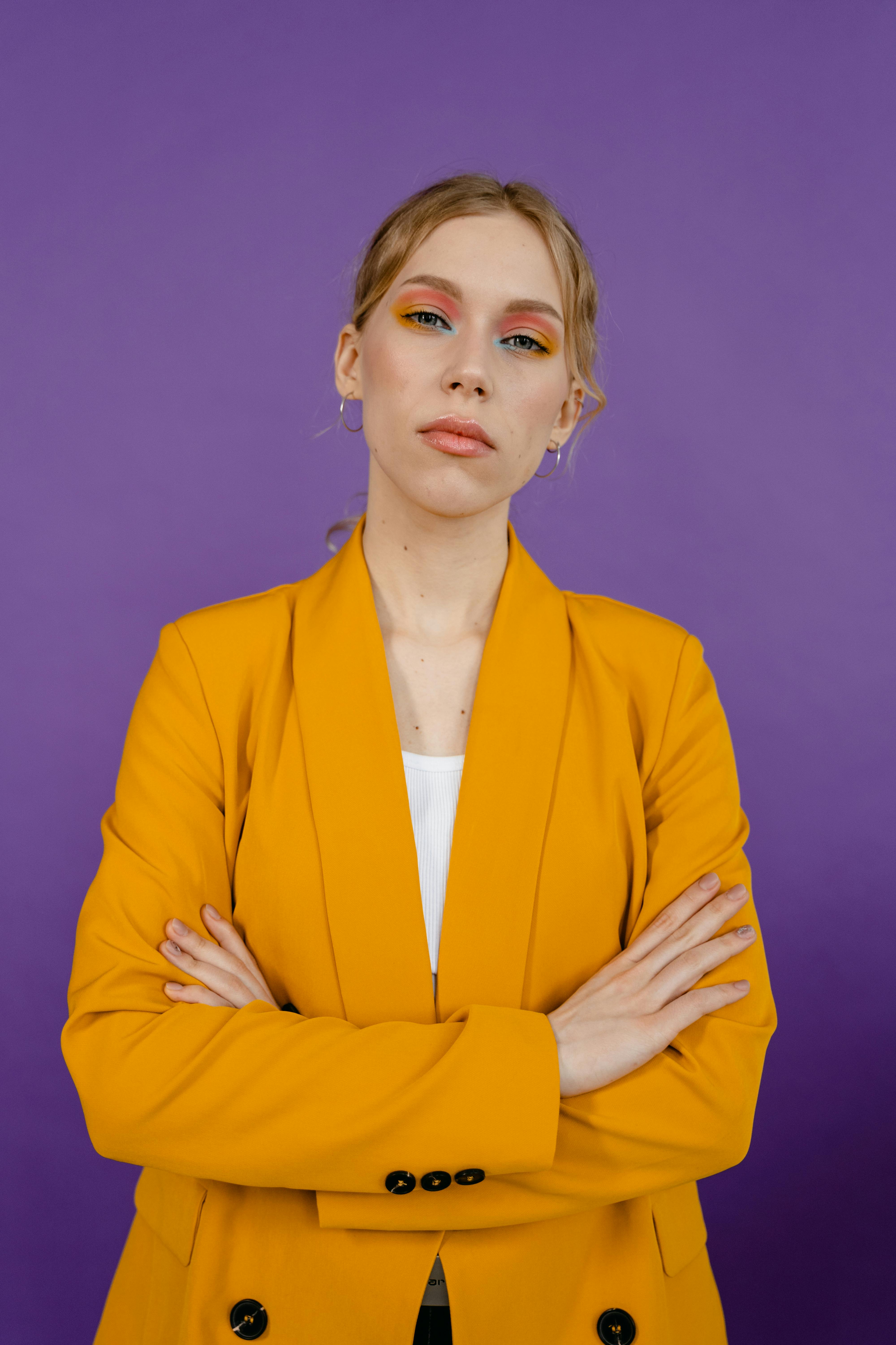 Femme frustrée en costume jaune croisant les bras | Source : Pexels