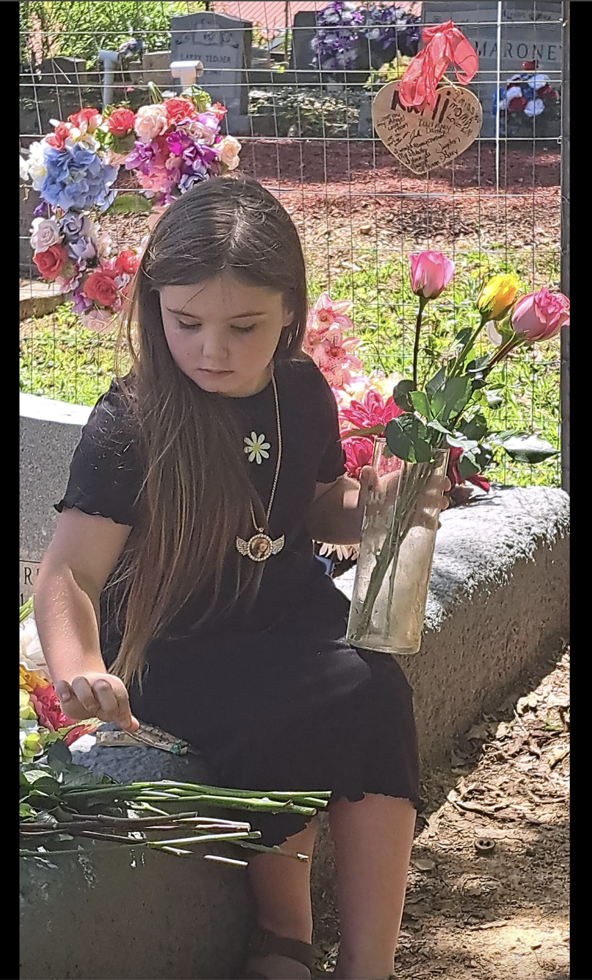 La petite Emouree Johnson est photographiée tenant des fleurs alors qu'elle est assise à côté de la tombe de sa mère, comme on peut le voir dans un post daté du 13 mai 2024 | Source : Facebook/jennifer.bordner