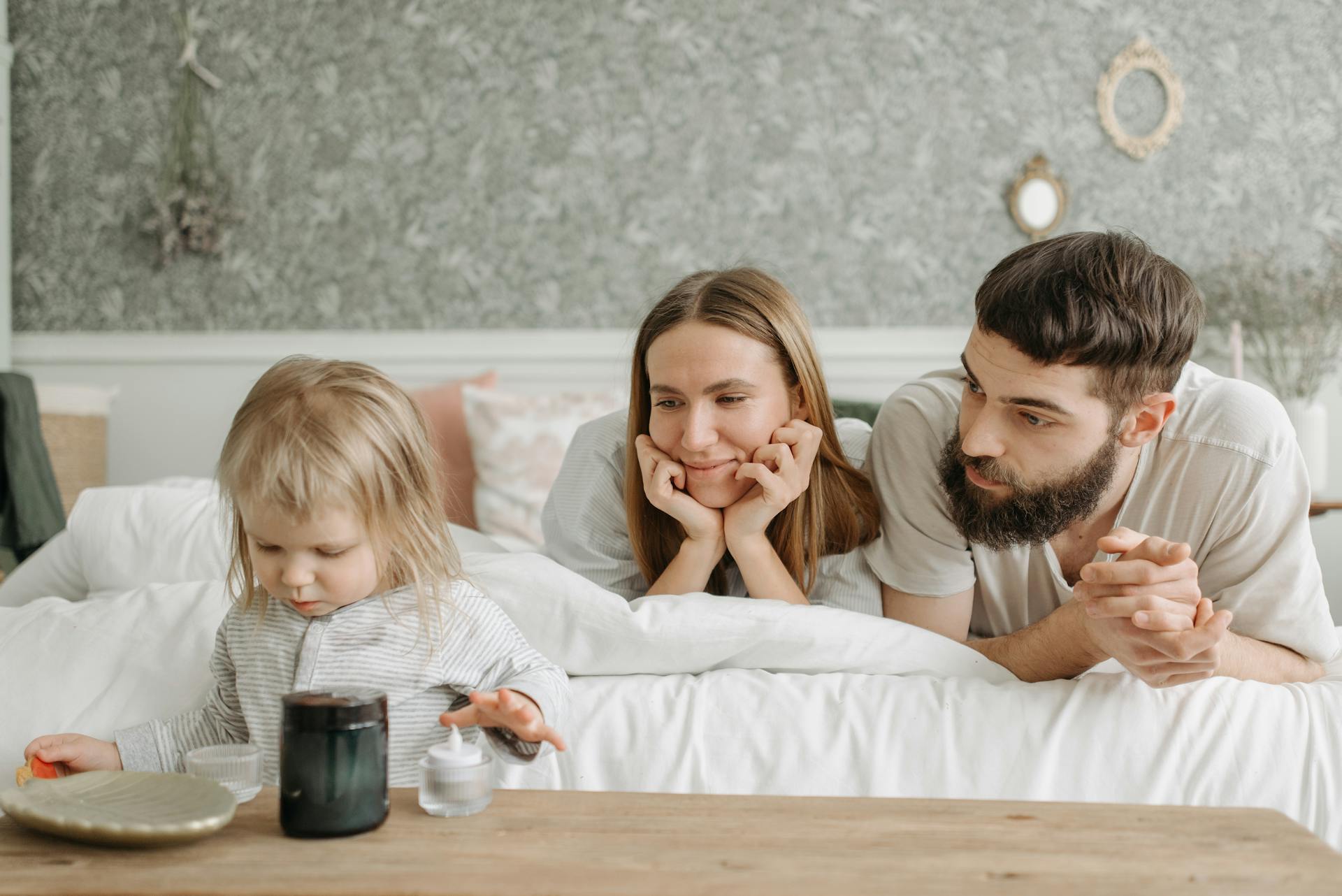 Un couple allongé sur le lit et regardant leur enfant | Source : Pexels