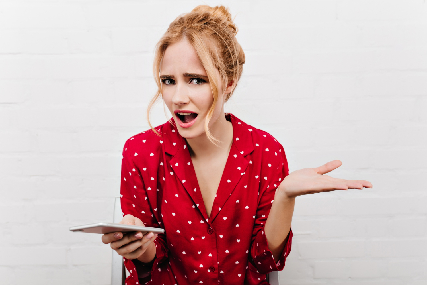 Une femme confuse tenant son téléphone | Source : Freepik