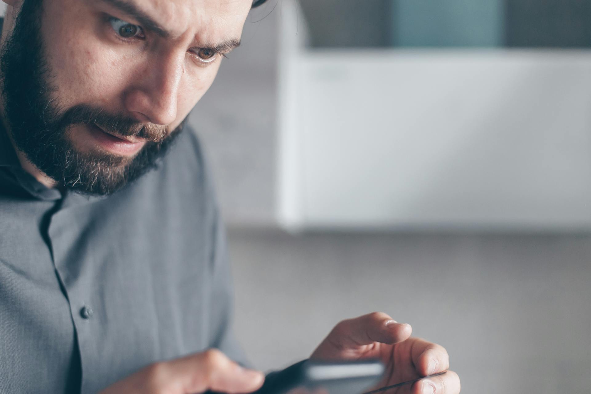 Un homme fixant son téléphone en état de choc | Source : Pexels