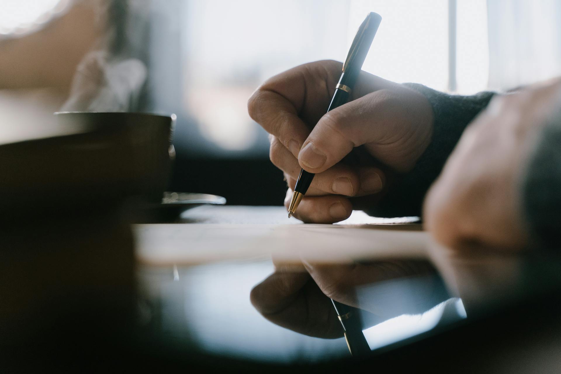 Un homme qui écrit avec un stylo | Source : Pexels