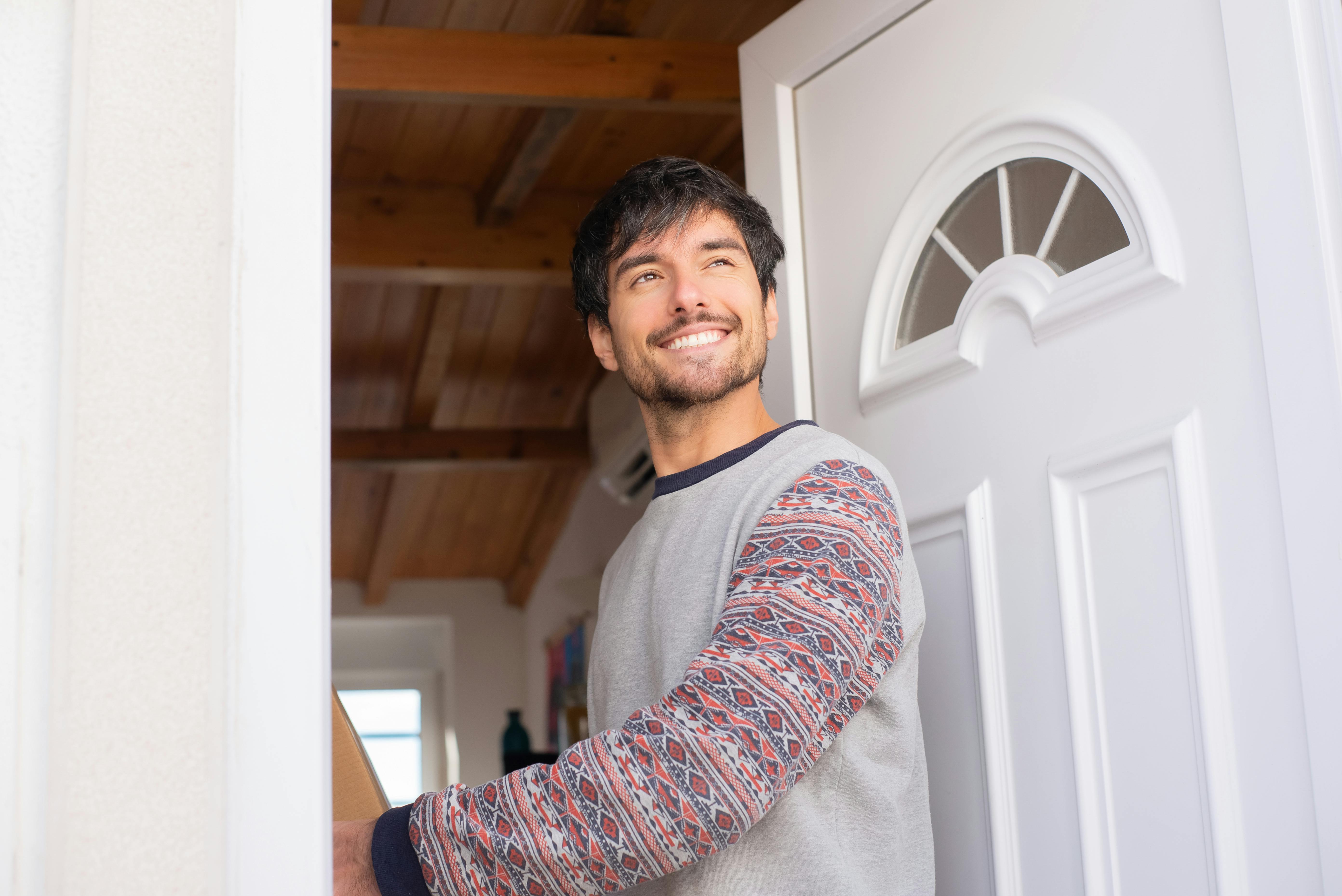 Un homme souriant alors qu'il se tient à l'entrée de la porte | Source : Pexels