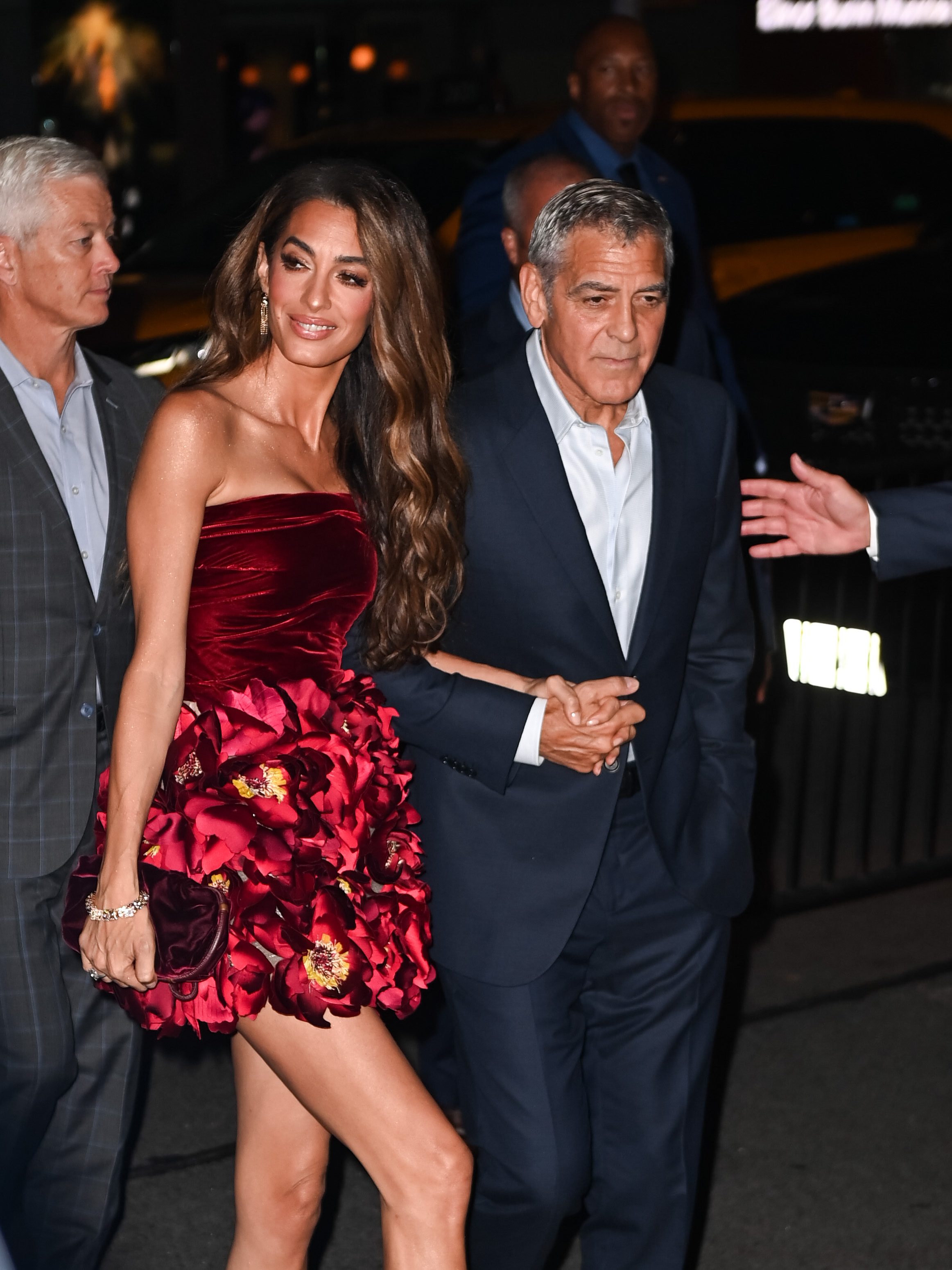 Amal Clooney fait son entrée bras dessus bras dessous avec George Clooney. Son doux sourire et sa chevelure ondulée attirent tous les regards avant même que les flashs des appareils photo ne commencent à crépiter.