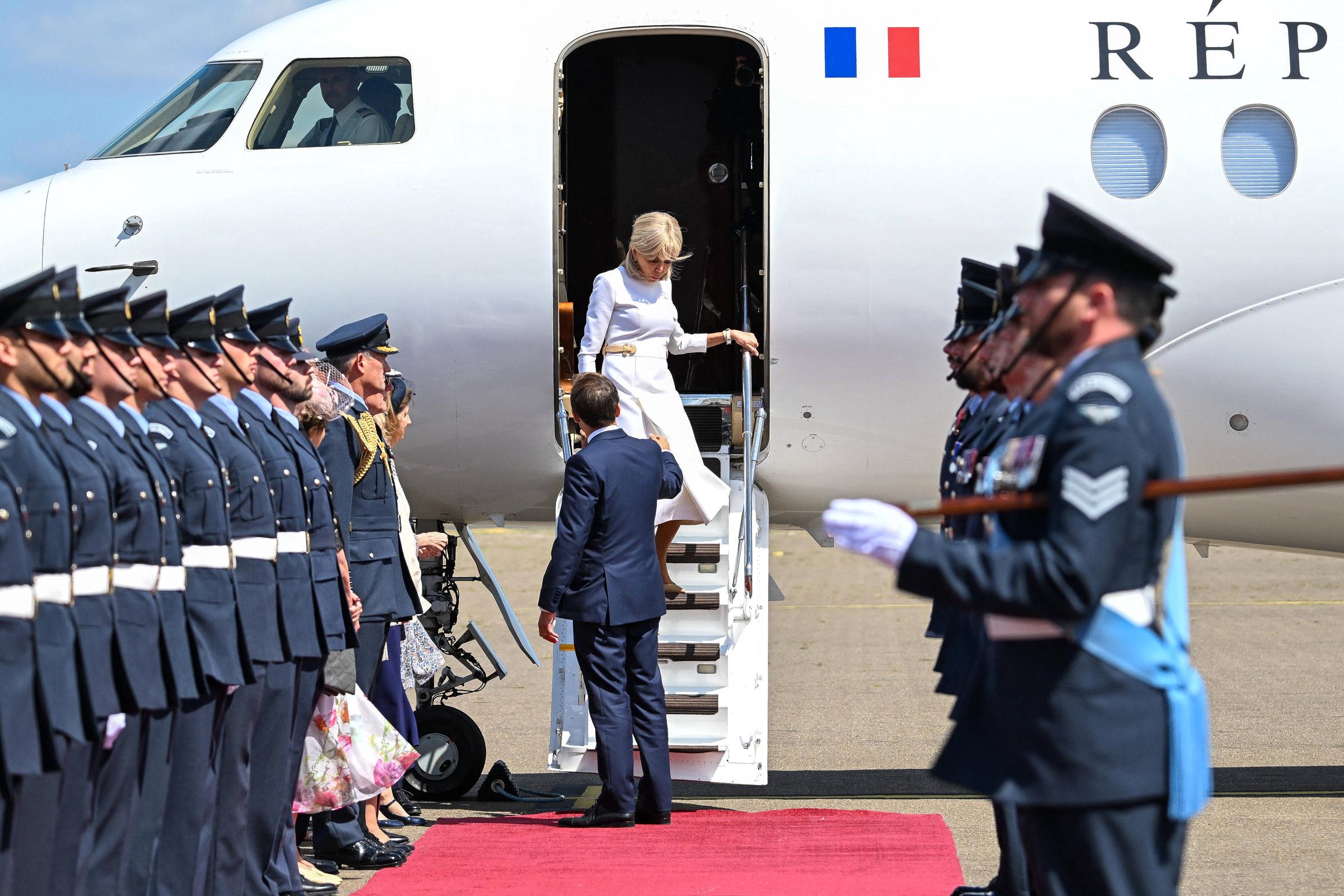 Emmanuel Macron tend la main à son épouse, Brigitte Macron, alors qu'elle descend les marches de l'avion. | Source : Getty Images