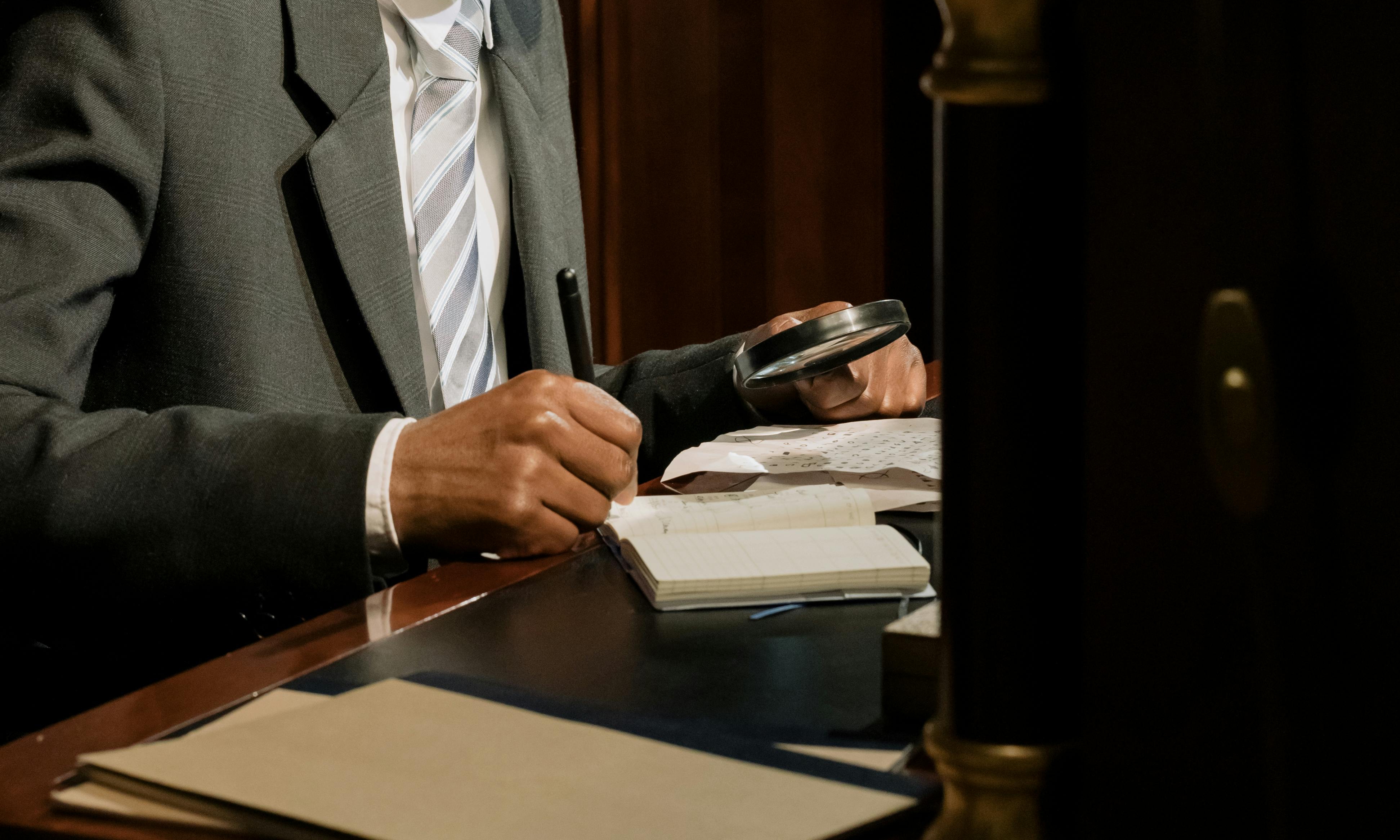 Un homme inspecte des documents à l'aide d'une loupe | Source : Pexels