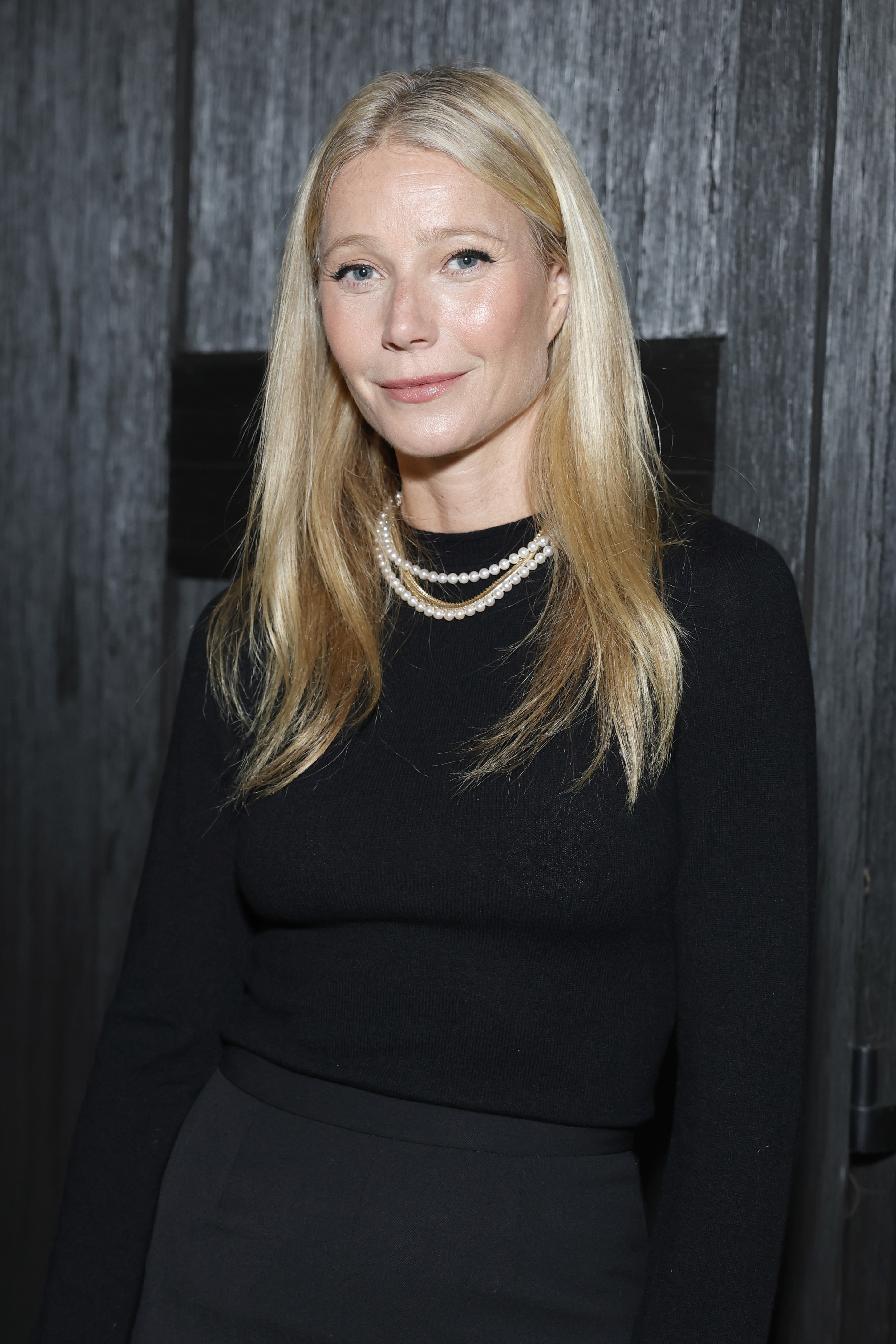 Gwyneth Paltrow assiste à l'événement « Gwyneth Paltrow and G. Label by goop host Holiday Celebration » à Los Angeles, en Californie, le 11 décembre 2023. Elle porte un ensemble noir ajusté associé à des colliers de perles superposés qui ajoutent une touche classique. Ses cheveux blonds raides sont séparés au milieu, et son maquillage naturel avec une touche de blush rosé lui donne un look discret et raffiné.