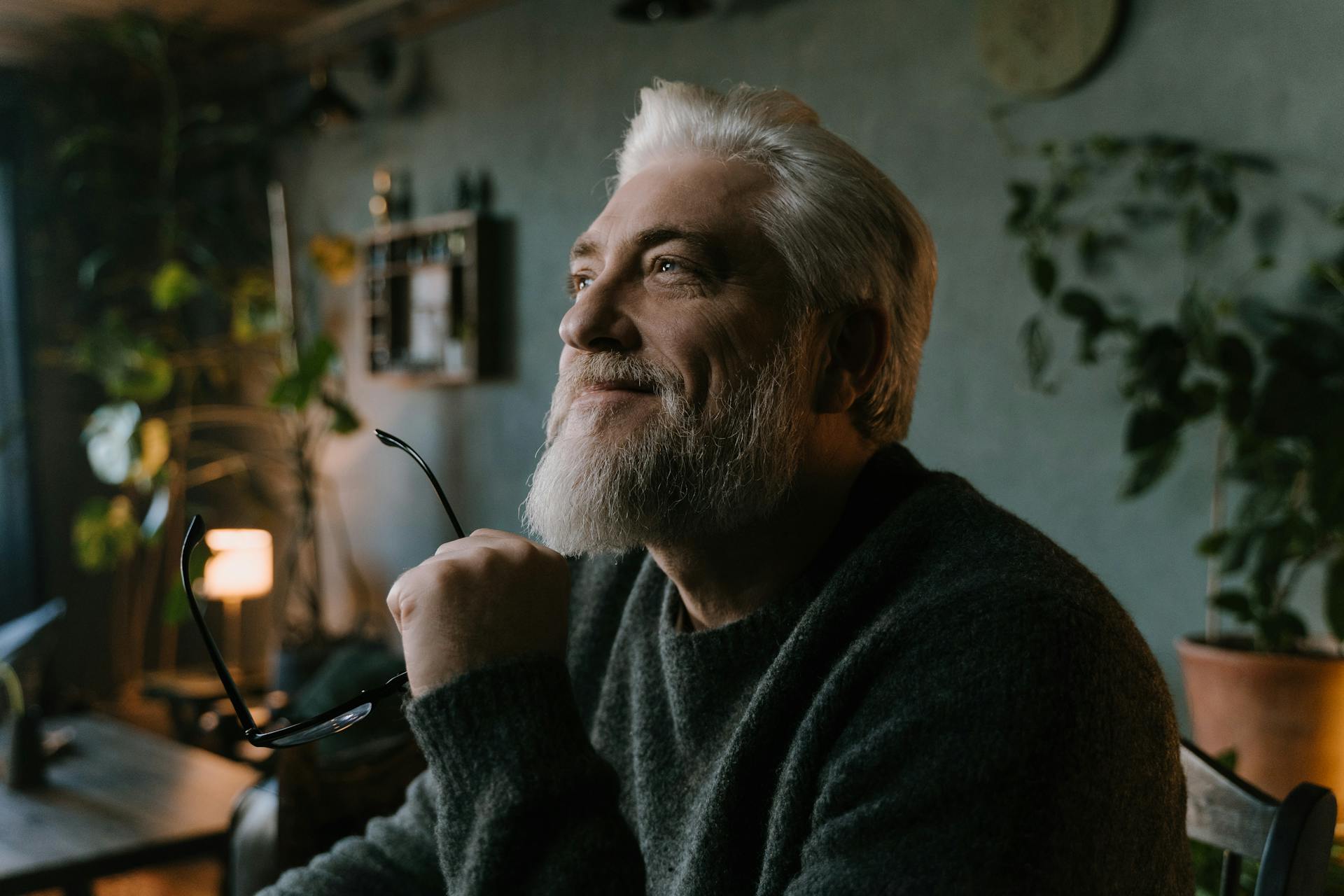 Un homme âgé souriant tout en tenant ses lunettes | Source : Pexels