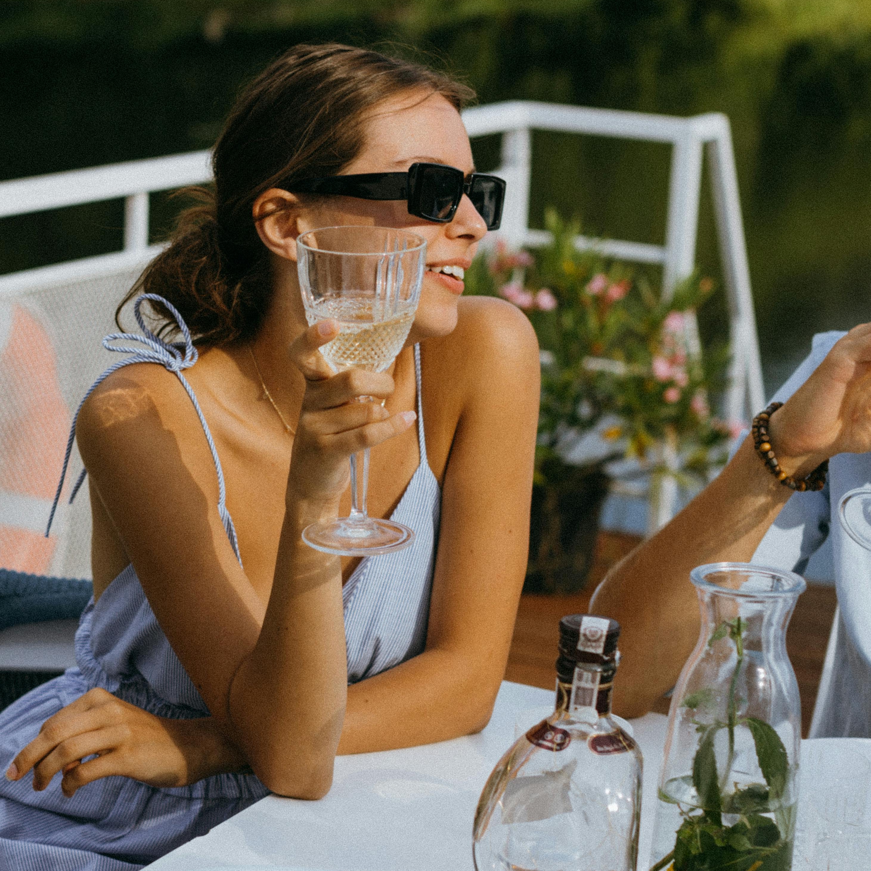 Une femme à bord d'un yacht brandit un verre en signe de célébration | Source : Pexels