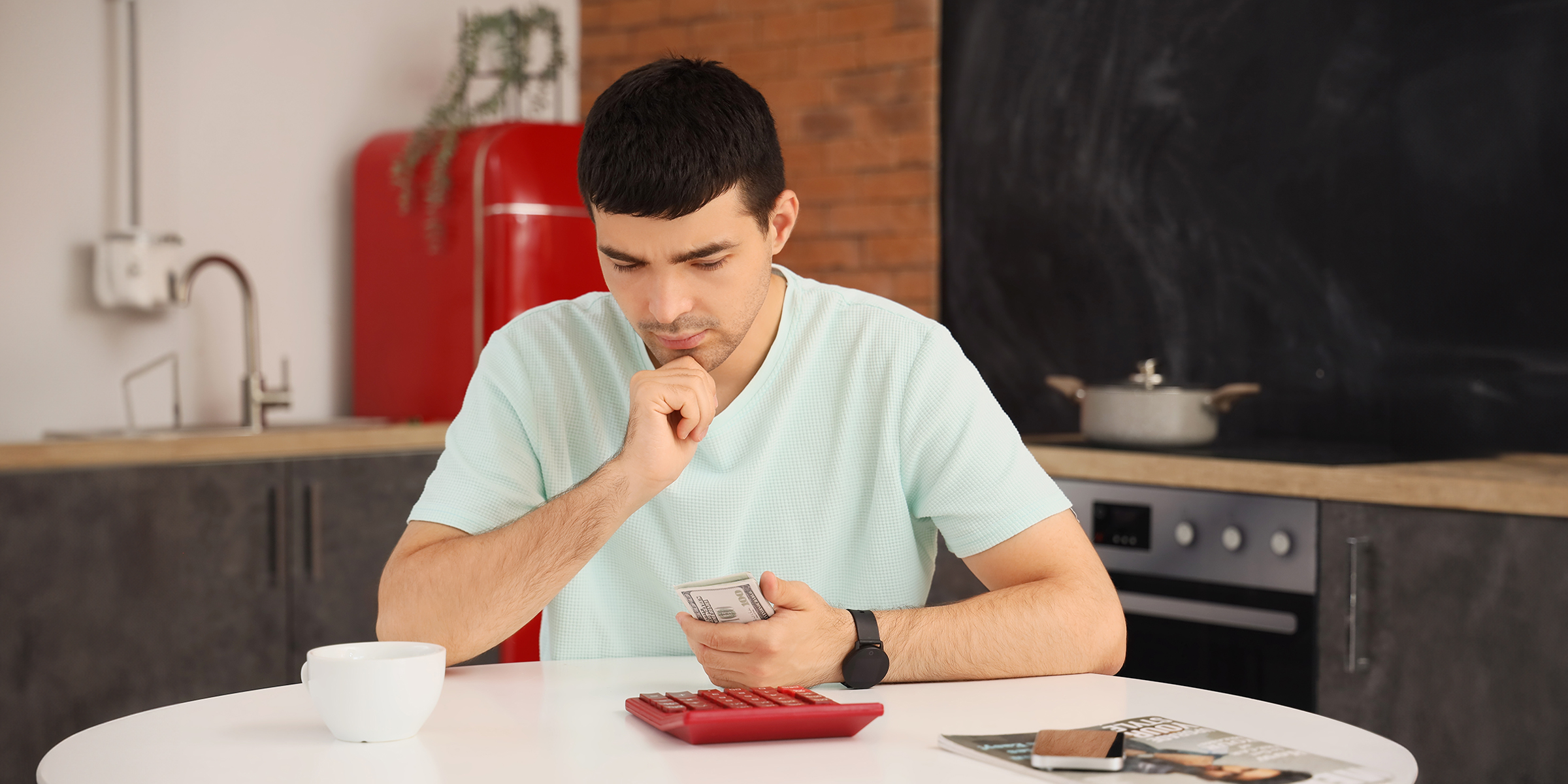 Un homme tenant une liasse de billets dans sa main à une table | Source : Shutterstock