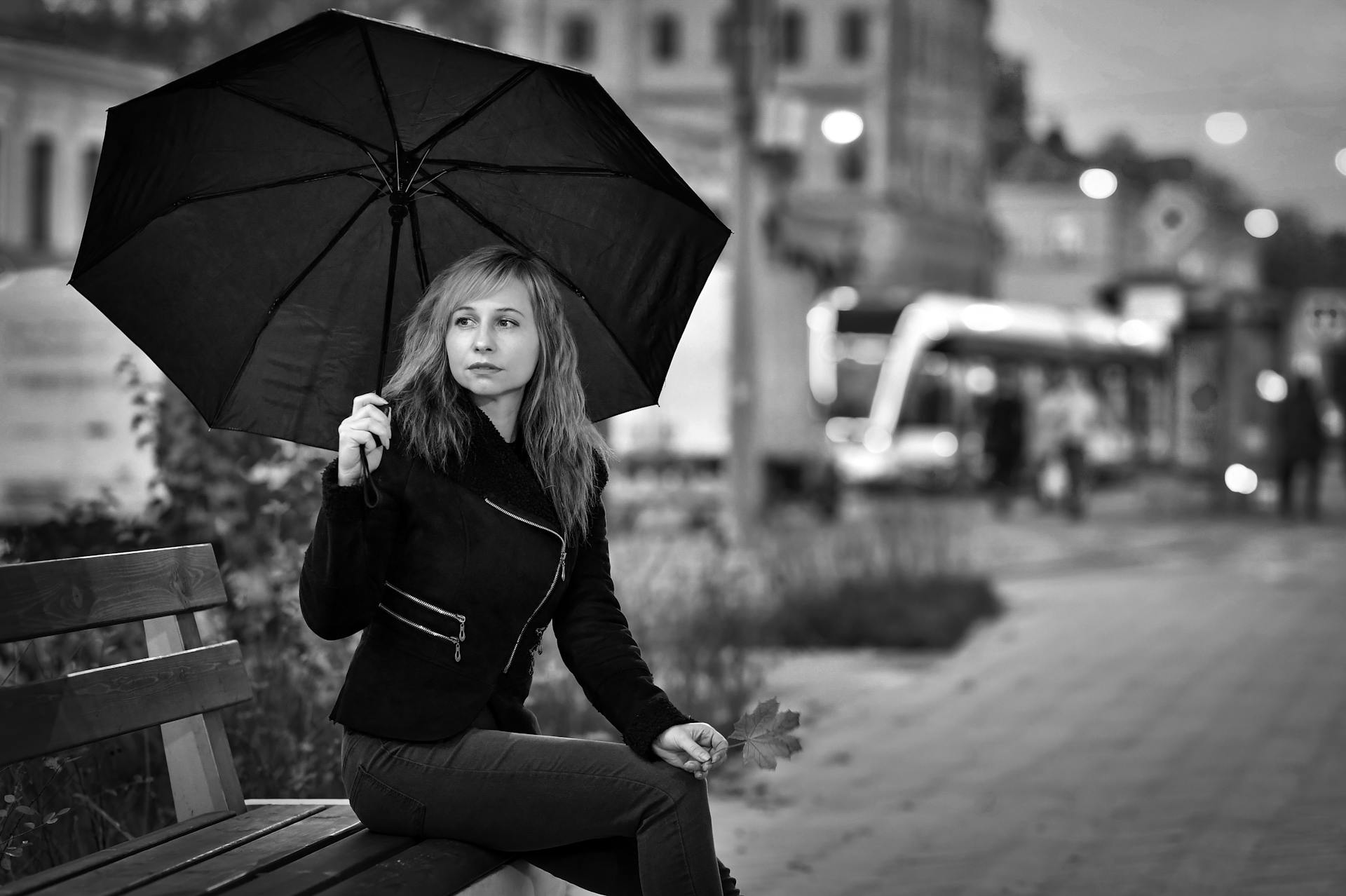 Une femme assise sur le banc tenant un parapluie | Source : Pexels