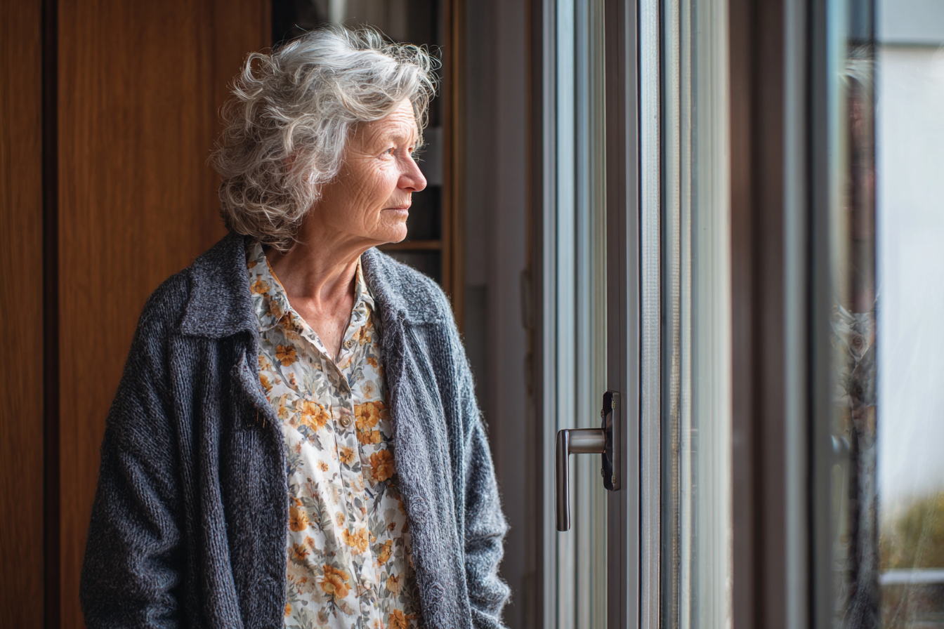 Une femme debout près d'une fenêtre | Source : Midjourney
