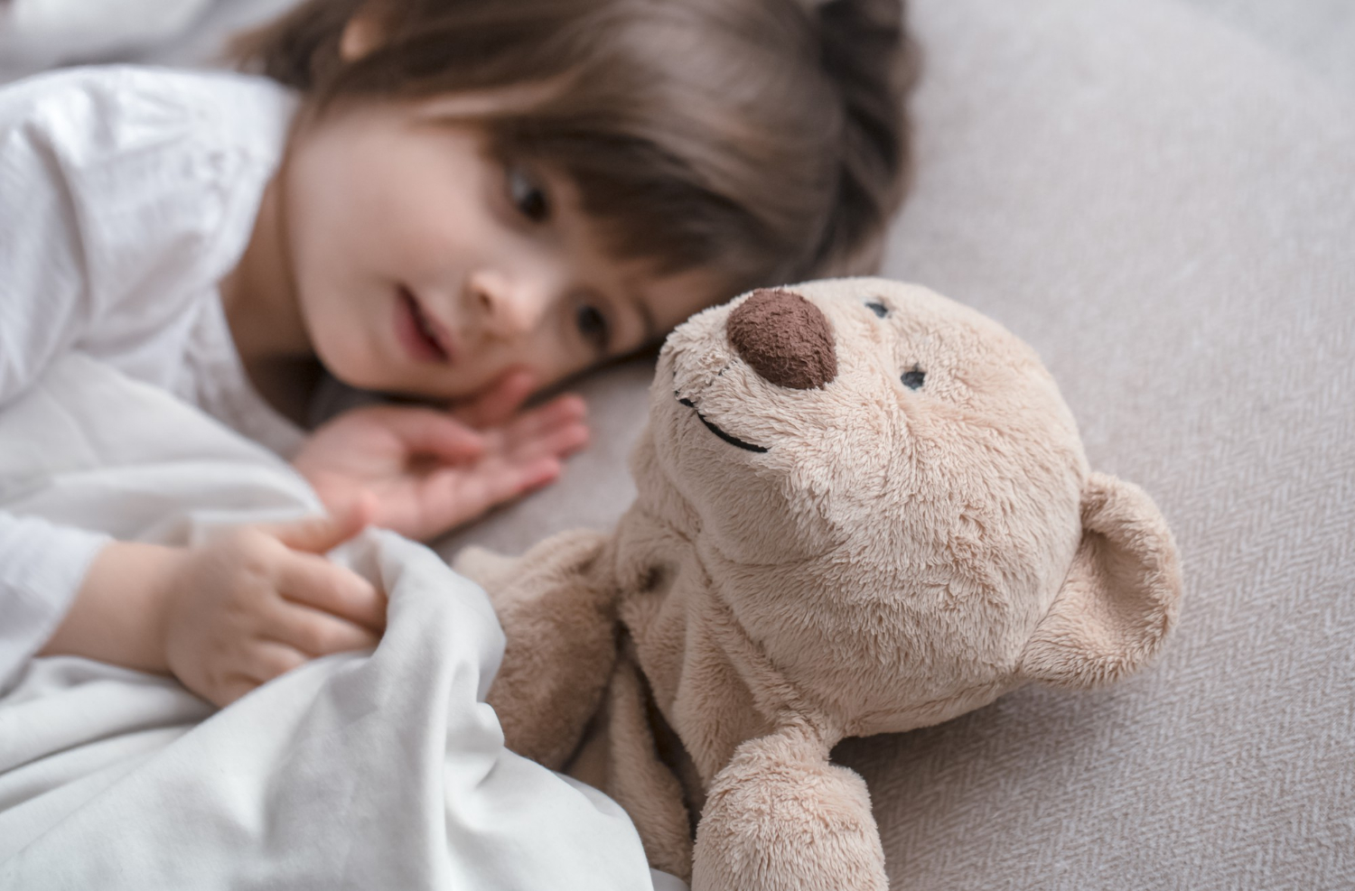 Une petite fille allongée à côté de son ours en peluche | Source : Freepik