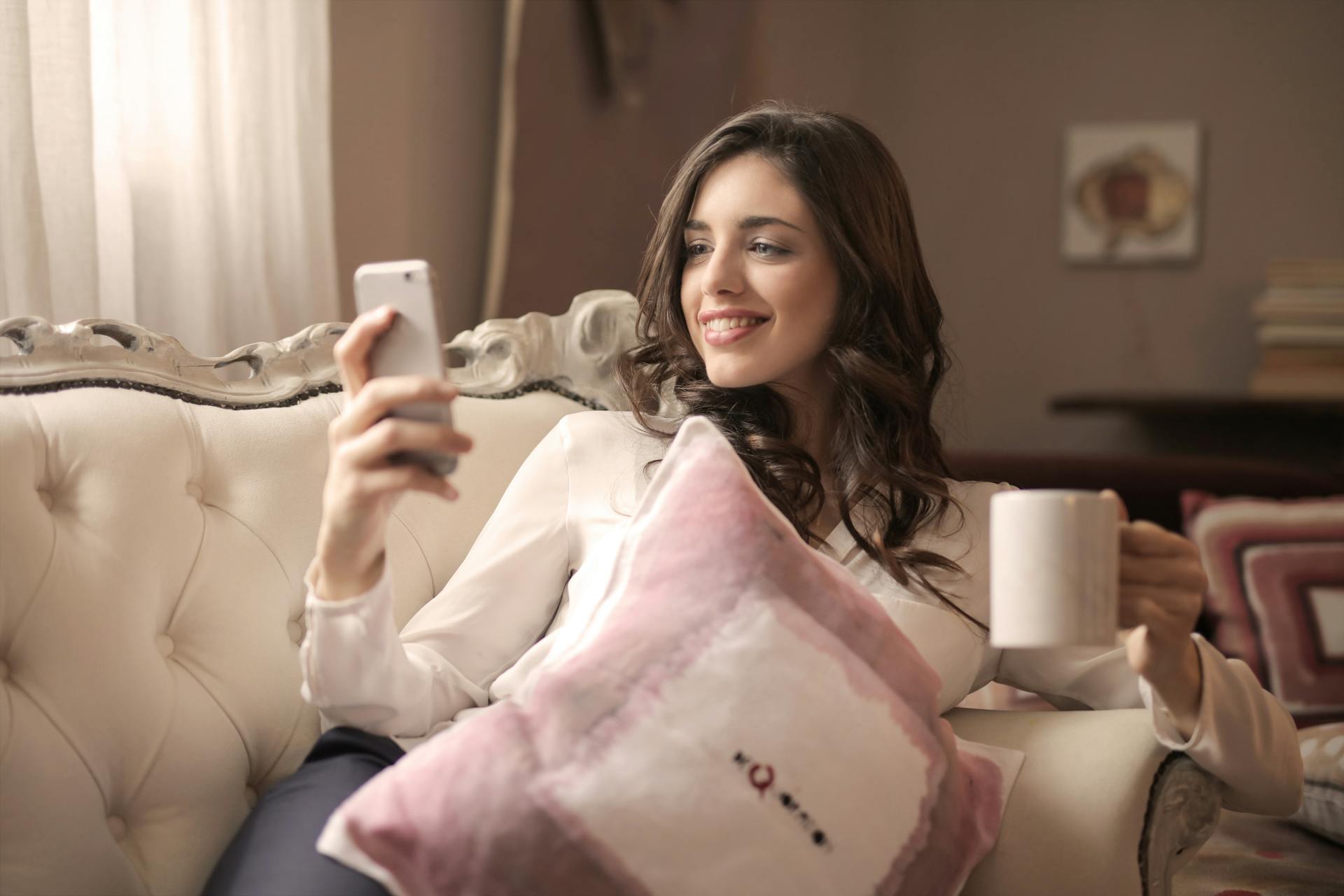 Une femme souriant à son téléphone | Source : Pexels