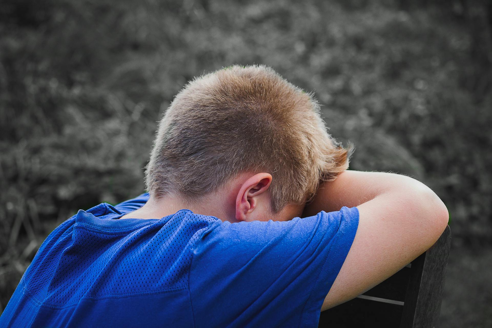 Un garçon triste appuyé sur une chaise en bois | Source : Pexels