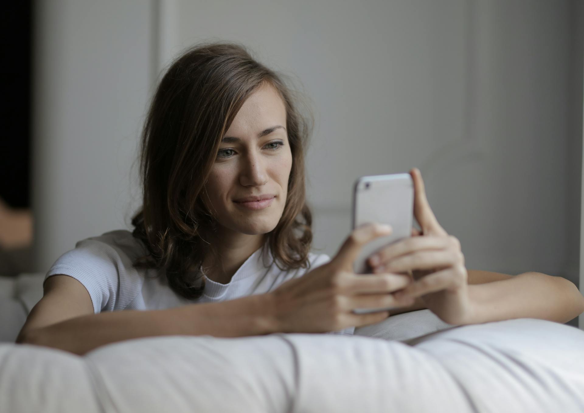 Une femme souriant à son téléphone | Source : Pexels