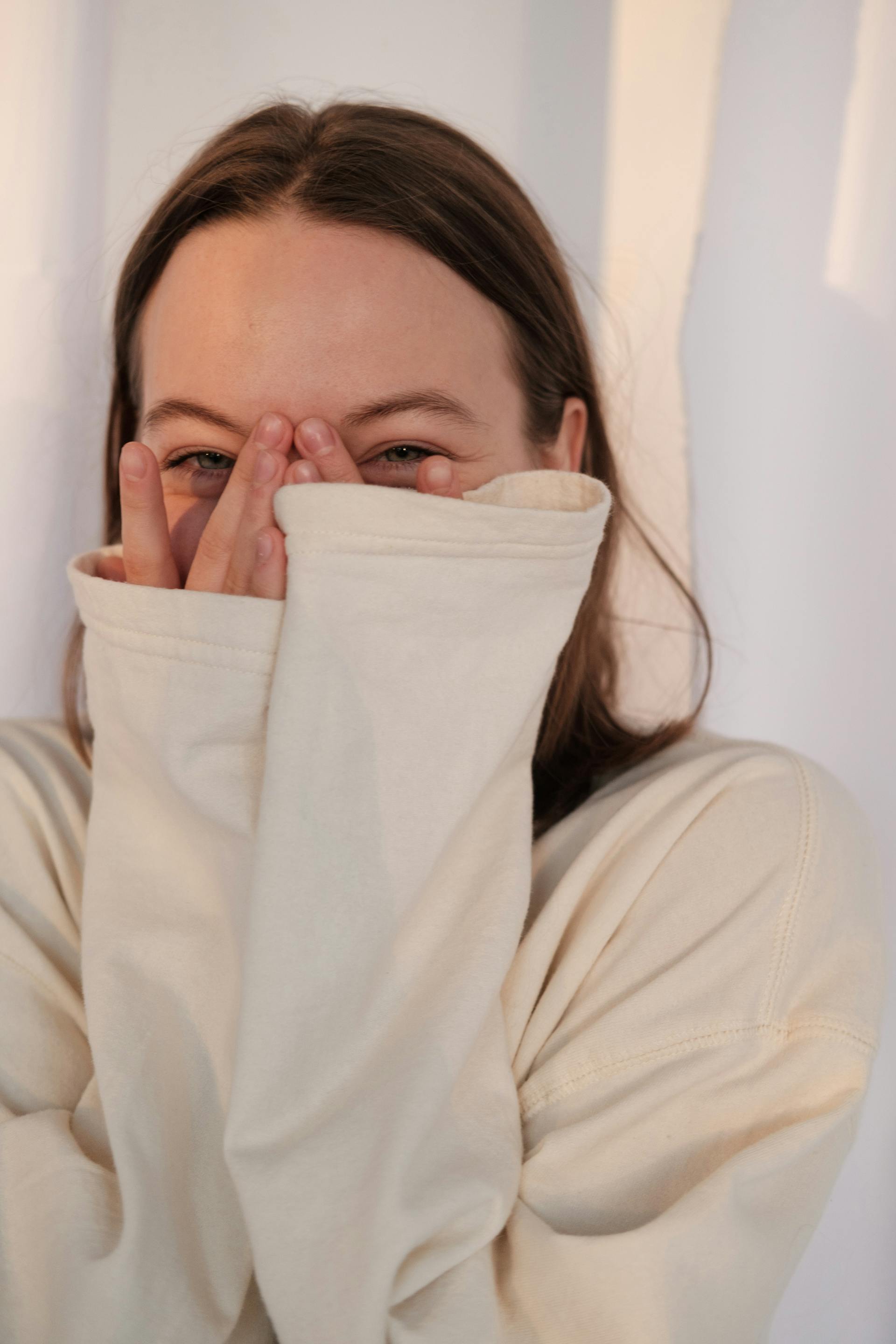 Une femme amusée qui jette un coup d'œil entre ses doigts | Source : Pexels