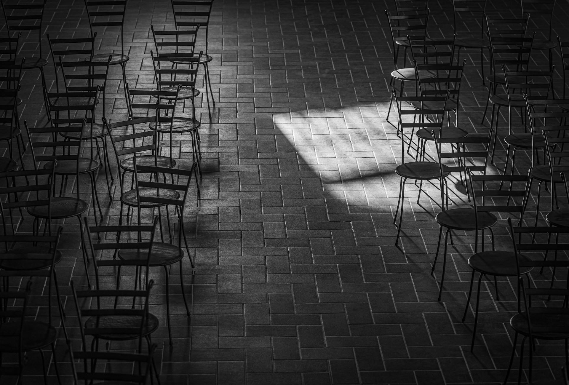 Photo en niveaux de gris de chaises dans une pièce vide | Source : Unsplash