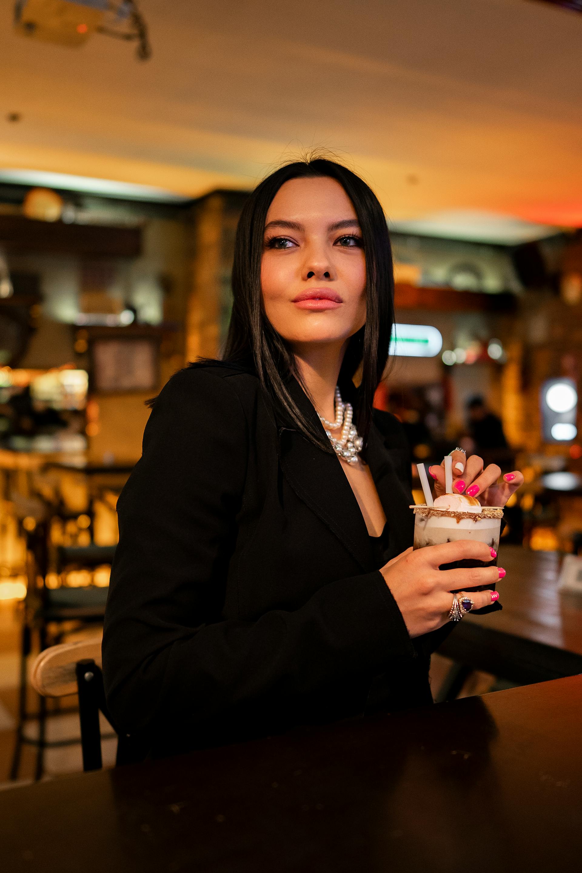 Une femme avec un cocktail debout dans un bar | Source : Pexels
