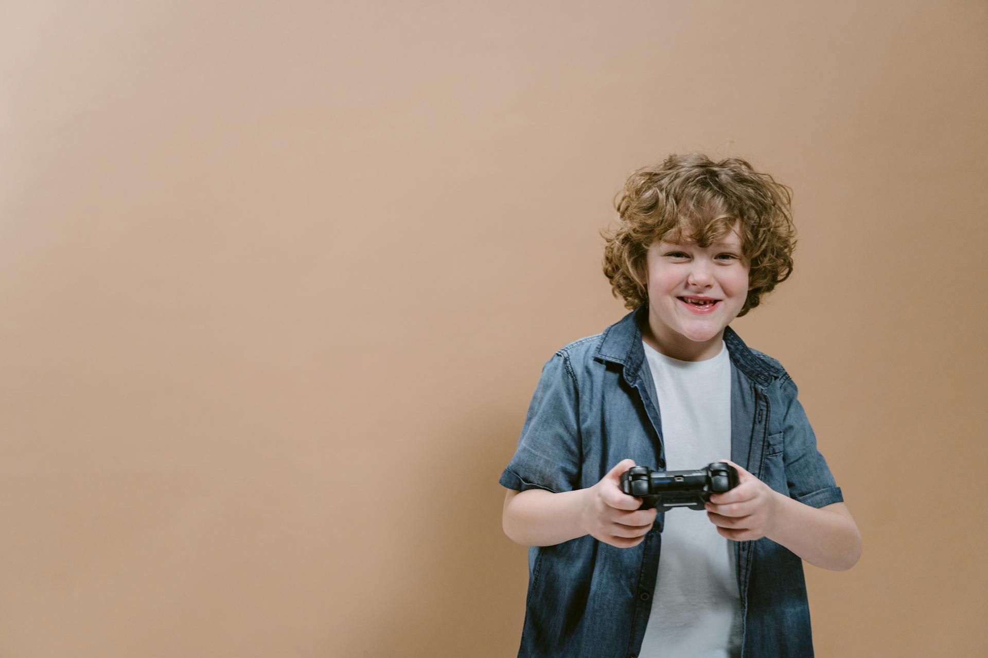 Un adolescent heureux tenant une manette | Source : Pexels